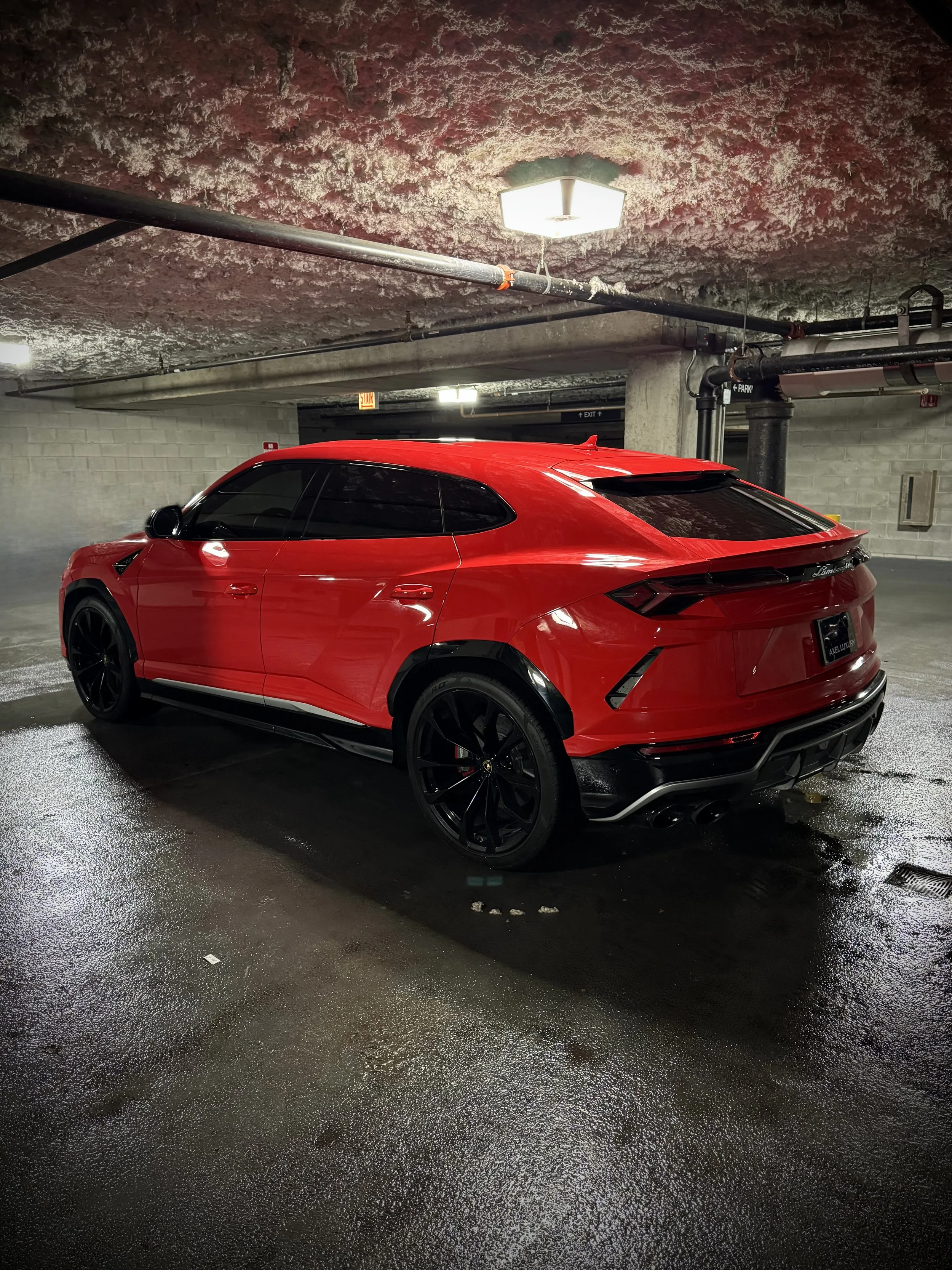 Red Lamborghini Urus parked in an urban luxury setting