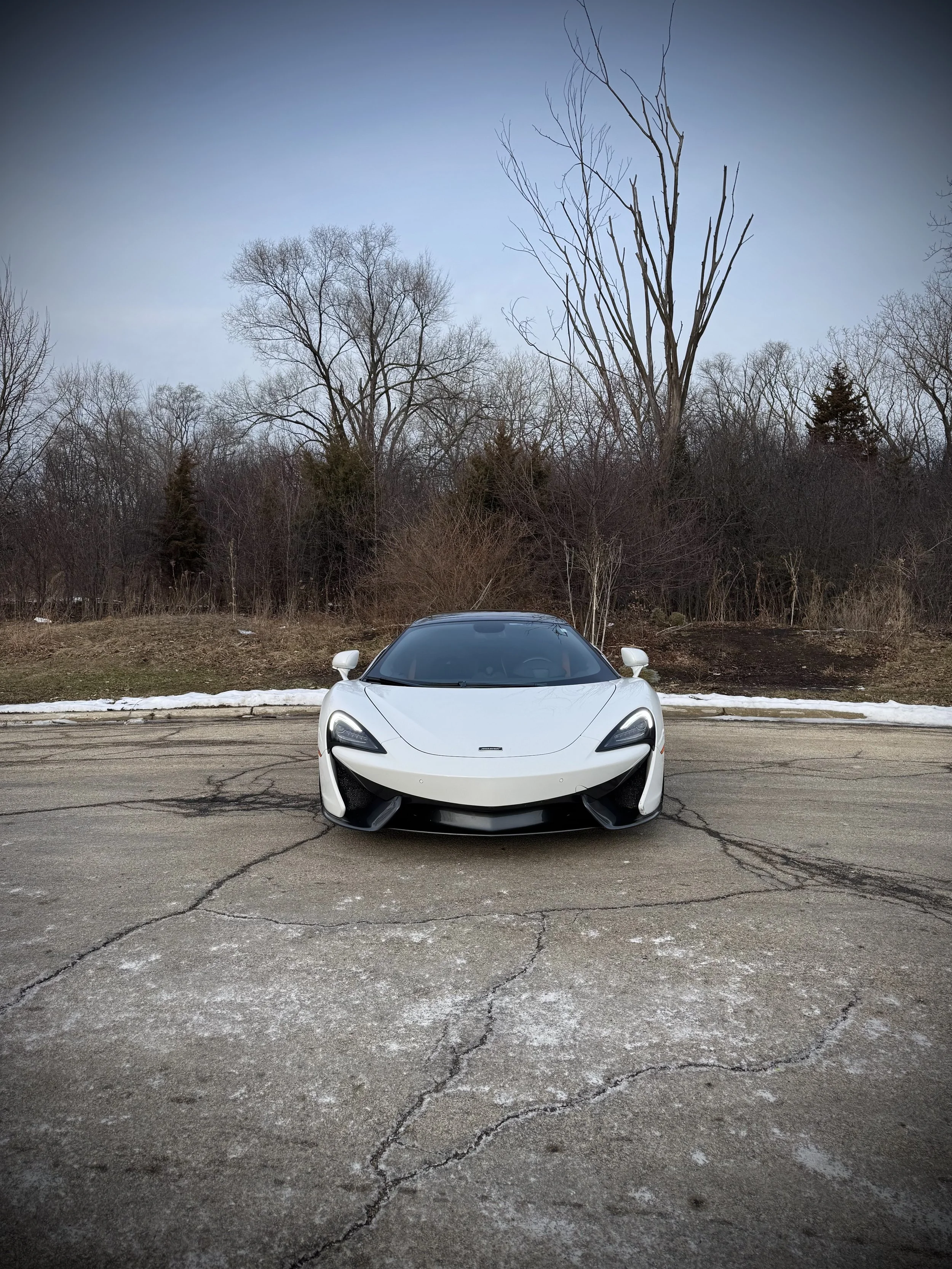 White McLaren 570S Spider with orange accents parked outdoors