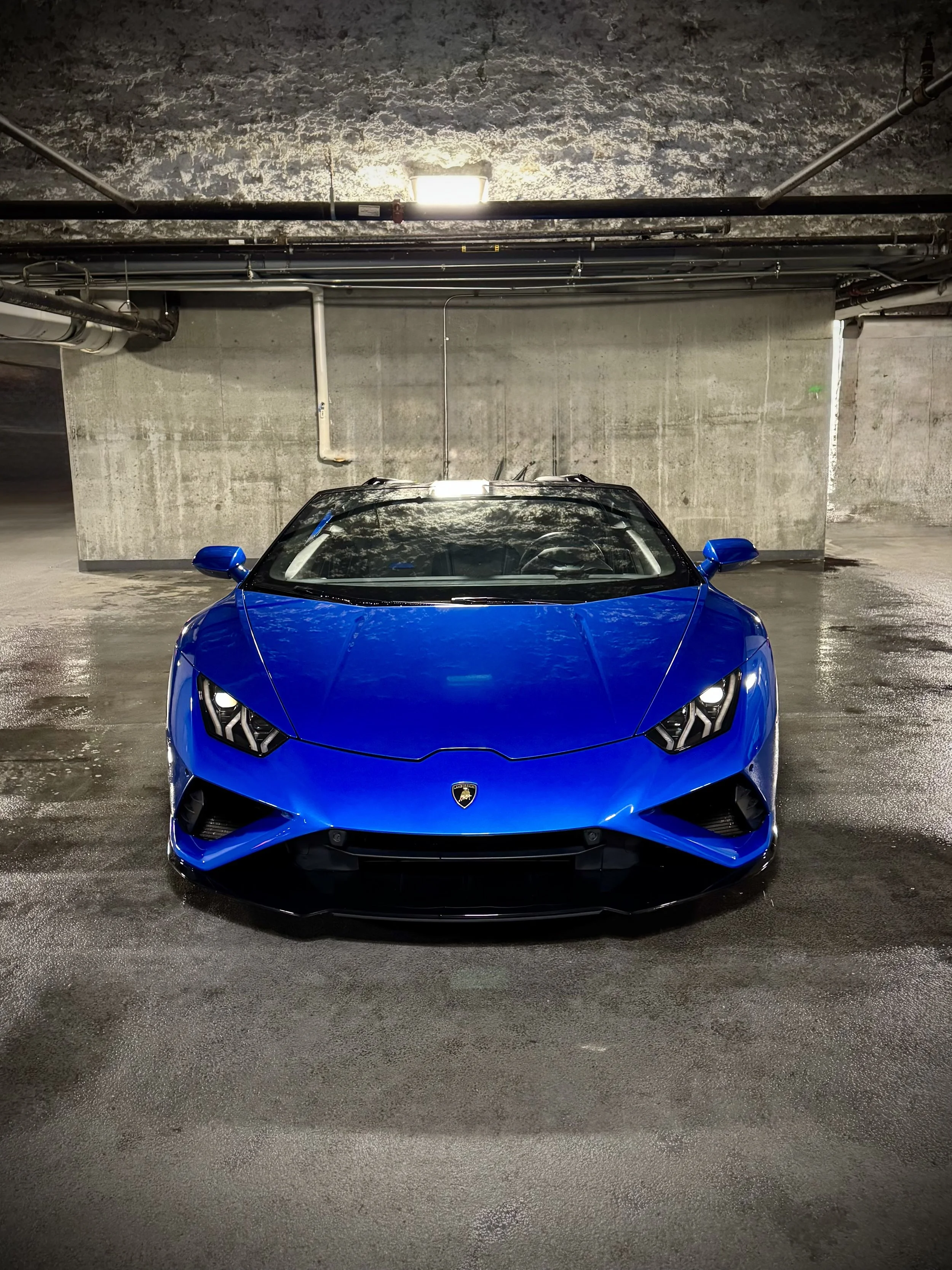Lamborghini Huracán Evo Spyder in metallic blue with yellow brake calipers parked in a garage.