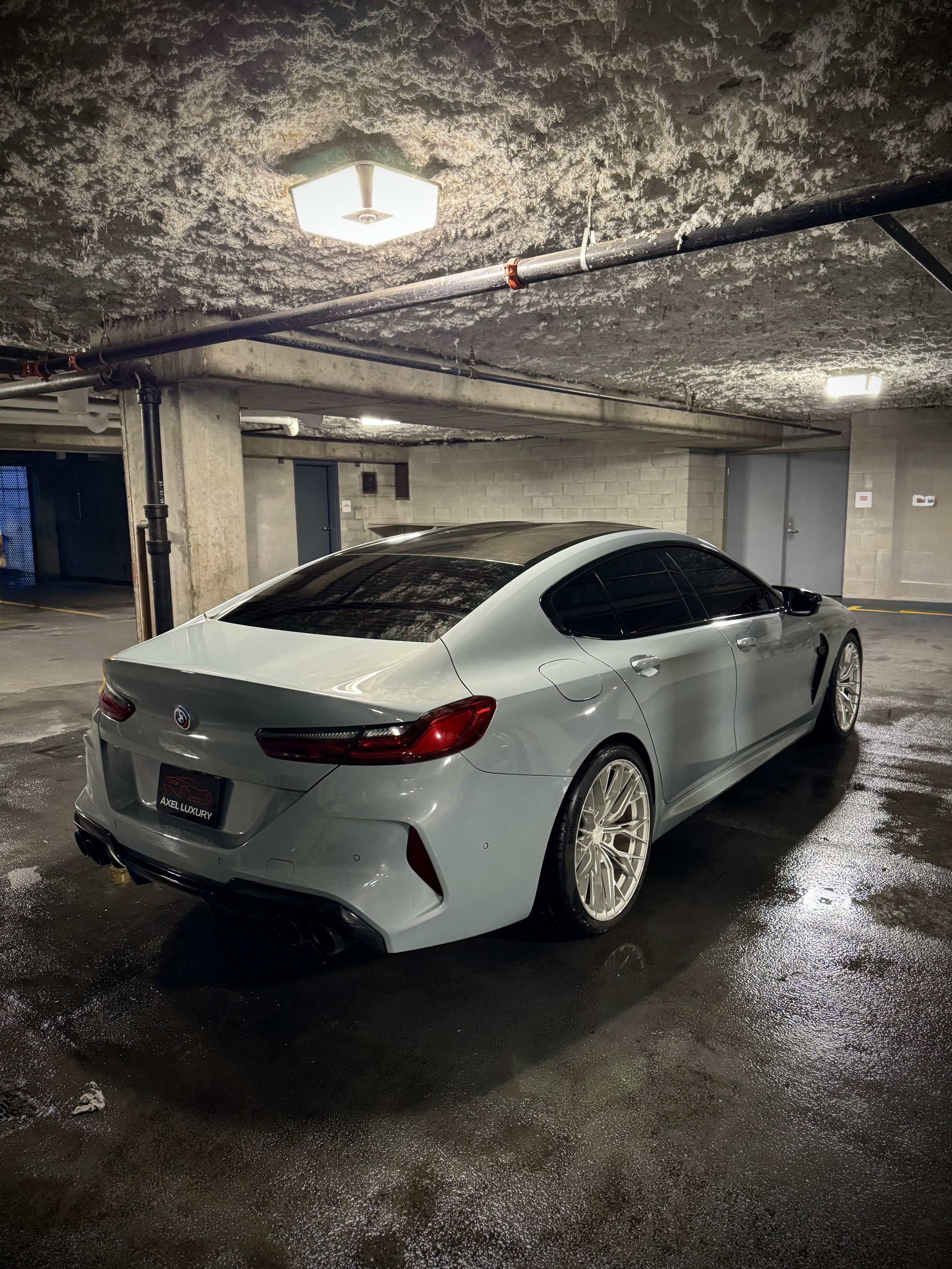 BMW M8 Competition in Nardo Gray with red leather interior and custom starlight ceiling parked outdoors.