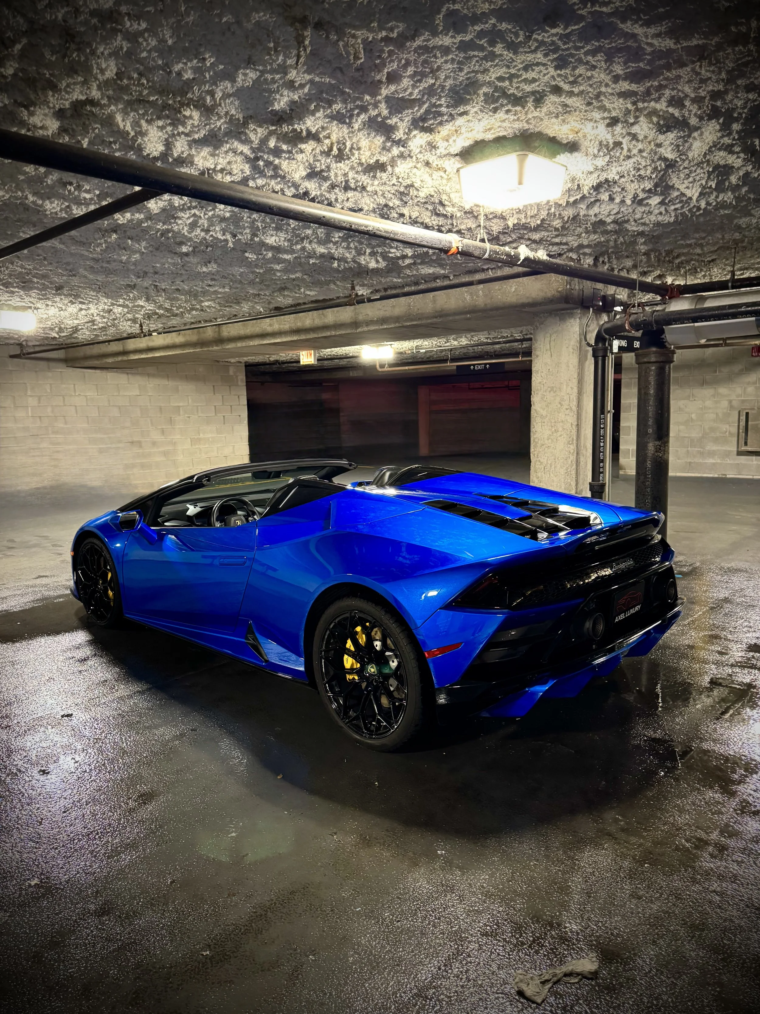 Lamborghini Huracán Evo Spyder in metallic blue with yellow brake calipers parked in a garage.
