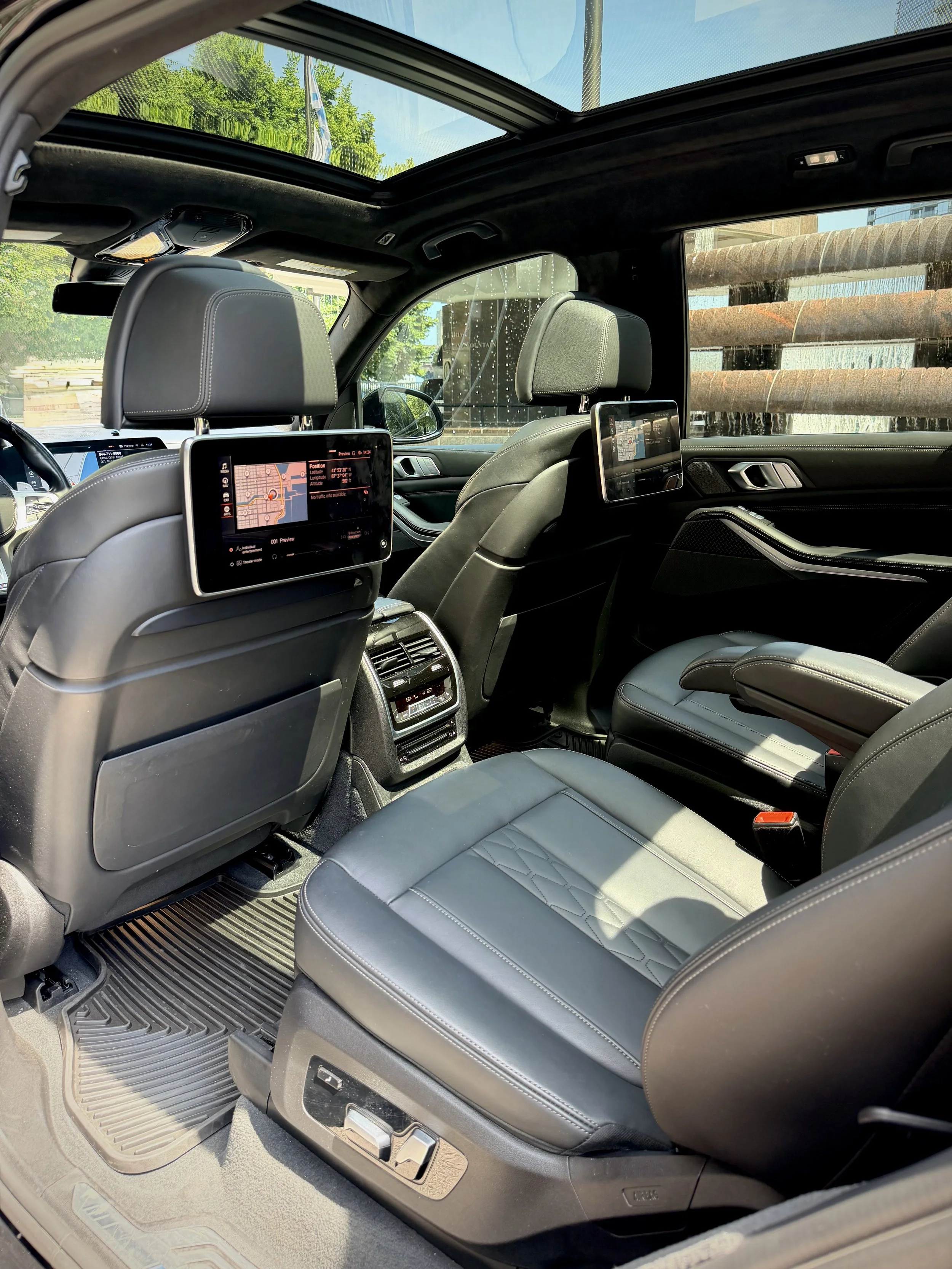 Gloss Black BMW X7 M50i luxury SUV with rear entertainment screens available for rental in Chicago.