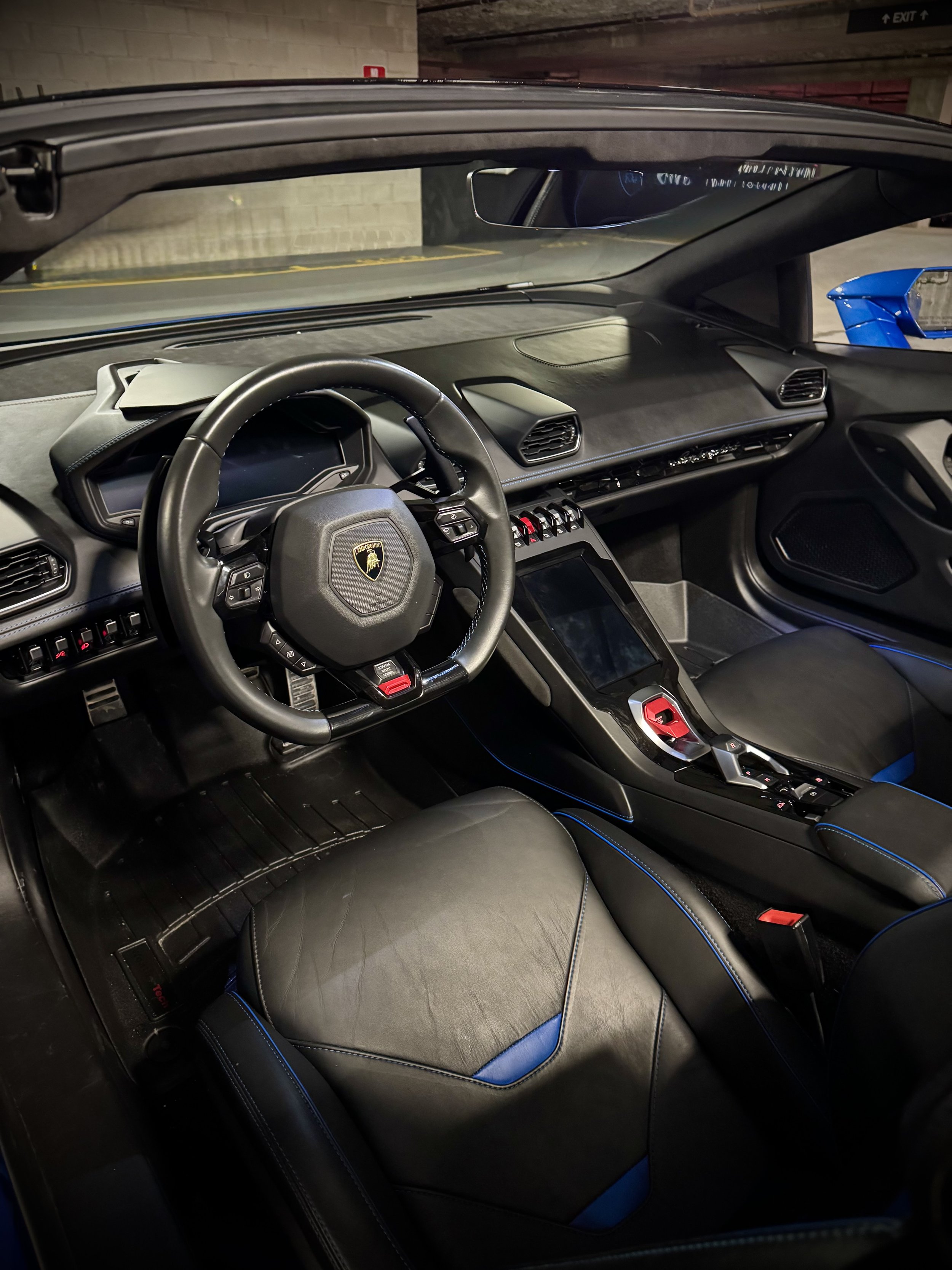 Lamborghini Huracán Evo Spyder in metallic blue with yellow brake calipers parked in a garage.