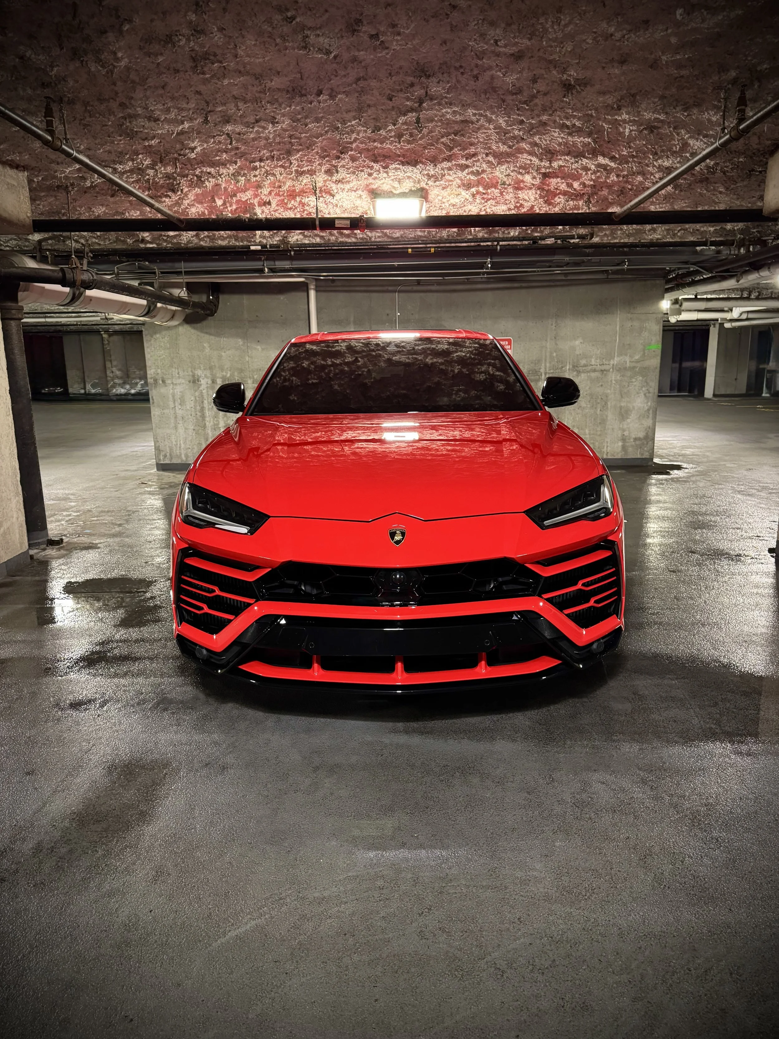 Red Lamborghini Urus parked in an urban luxury setting