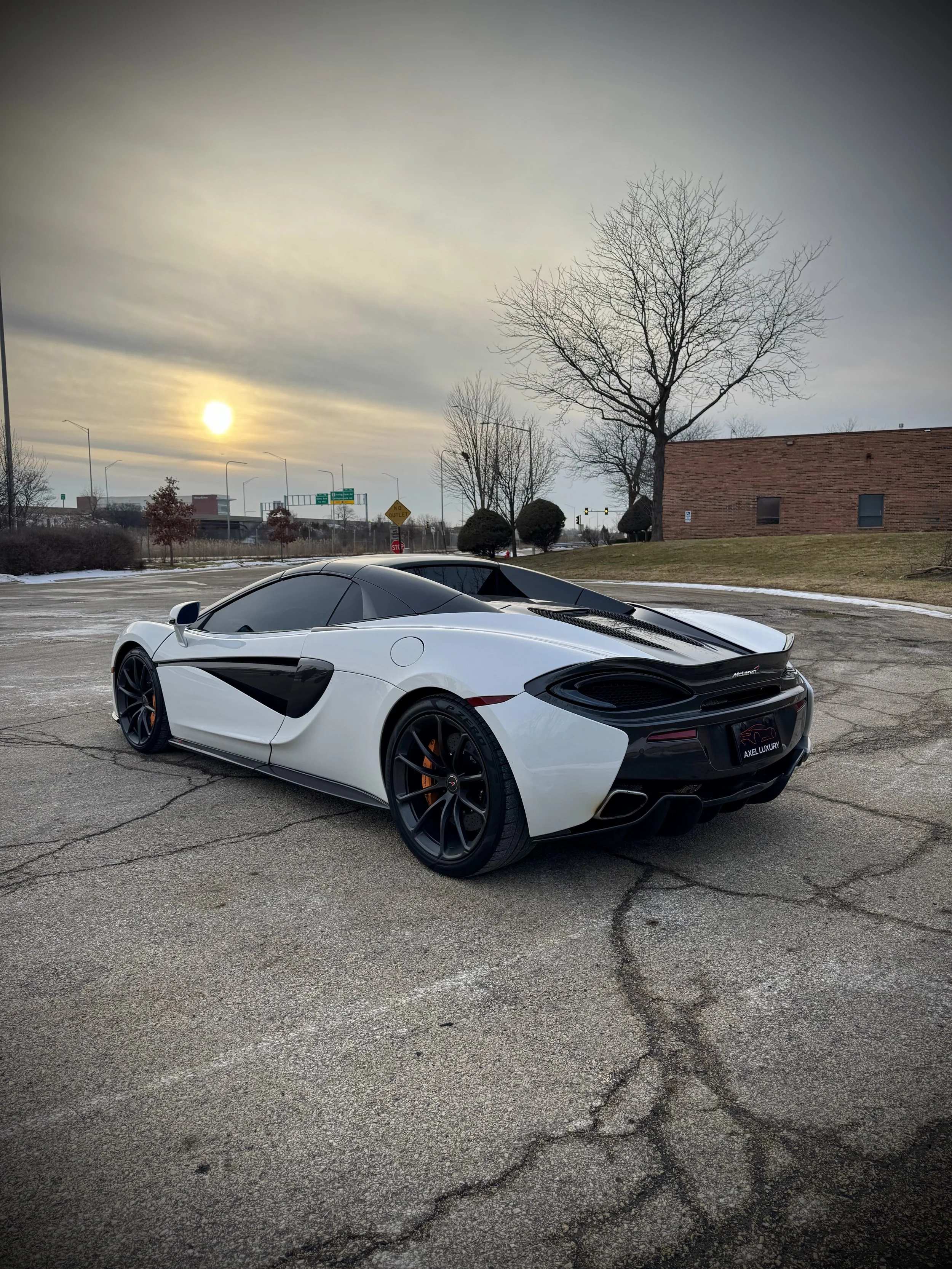 White McLaren 570S Spider with orange accents parked outdoors