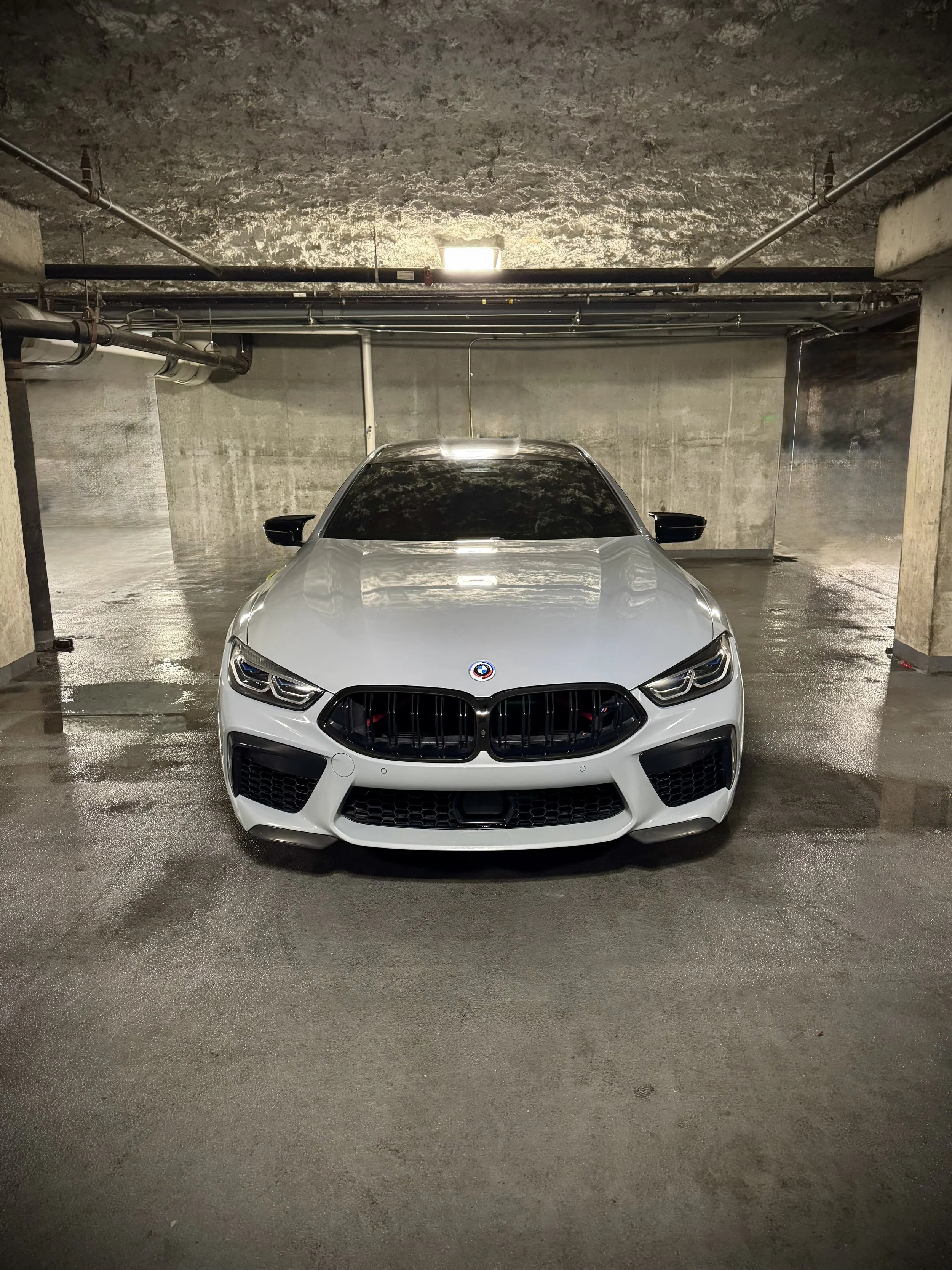 BMW M8 Competition in Nardo Gray with red leather interior and custom starlight ceiling parked outdoors.