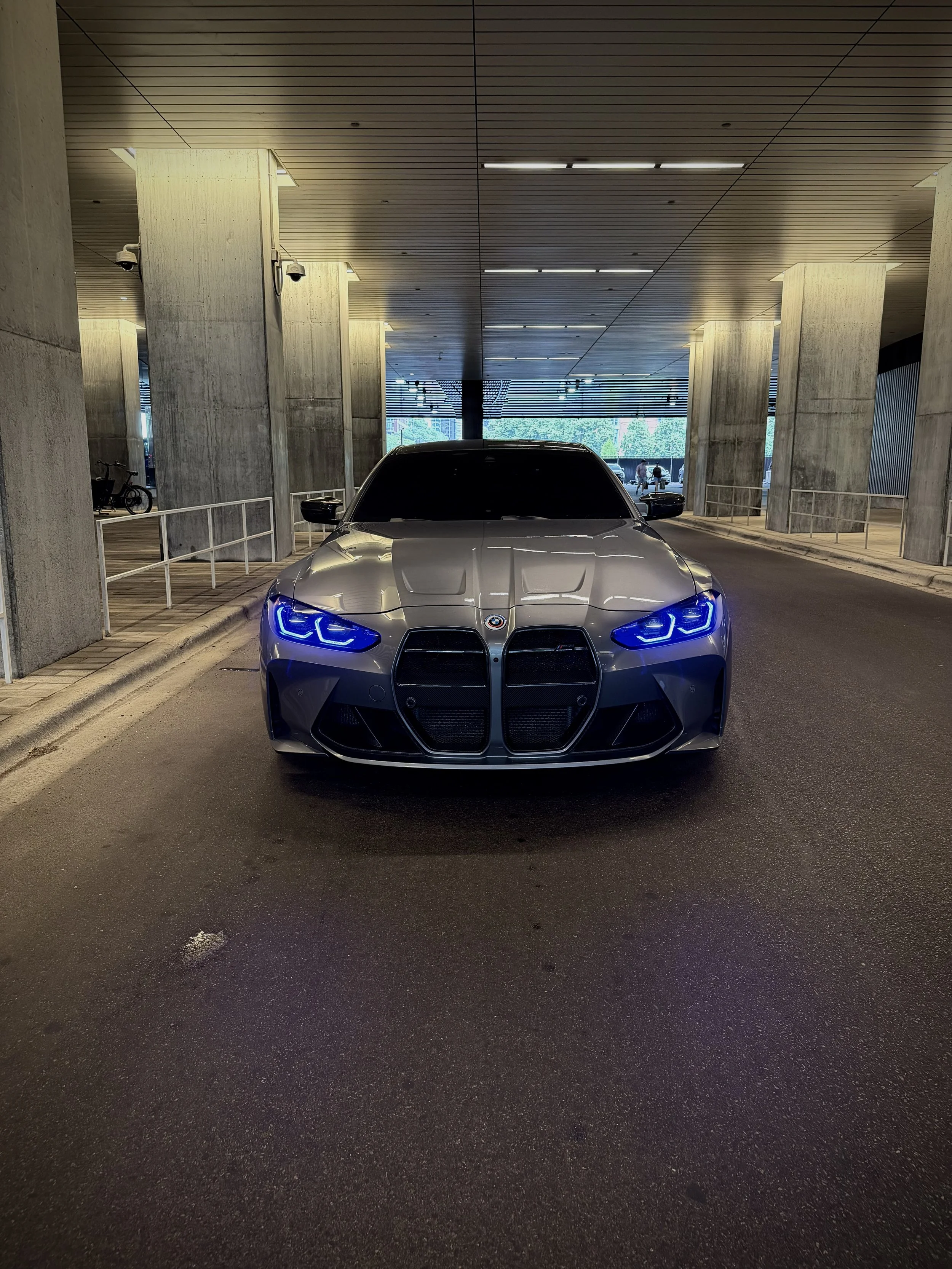 Metallic gray BMW M4 Competition parked in Chicago, featuring aggressive styling, black wheels, premium performance, and a twin-turbocharged engine available for luxury and exotic car rental.