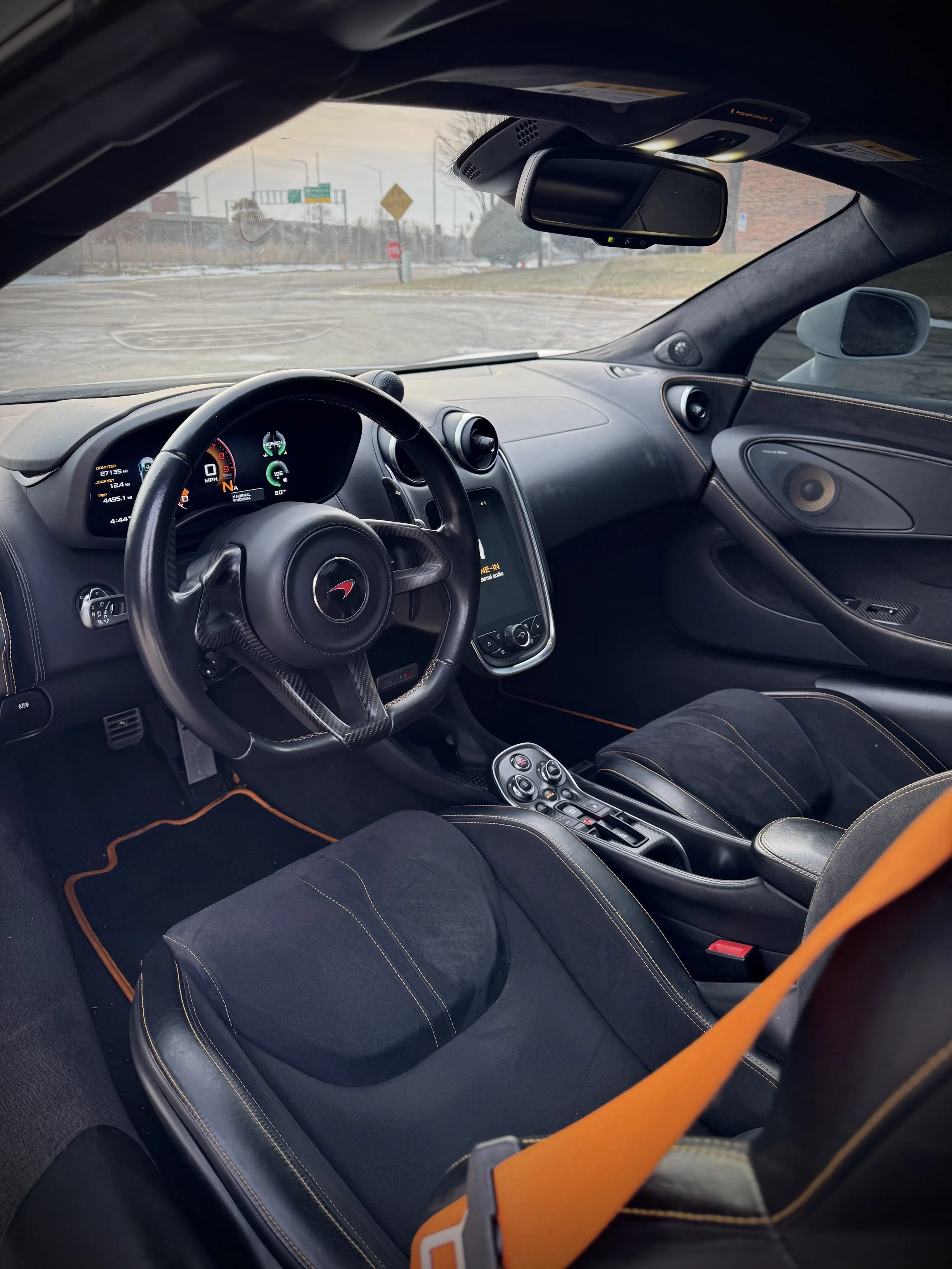 White McLaren 570S Spider with orange accents parked outdoors