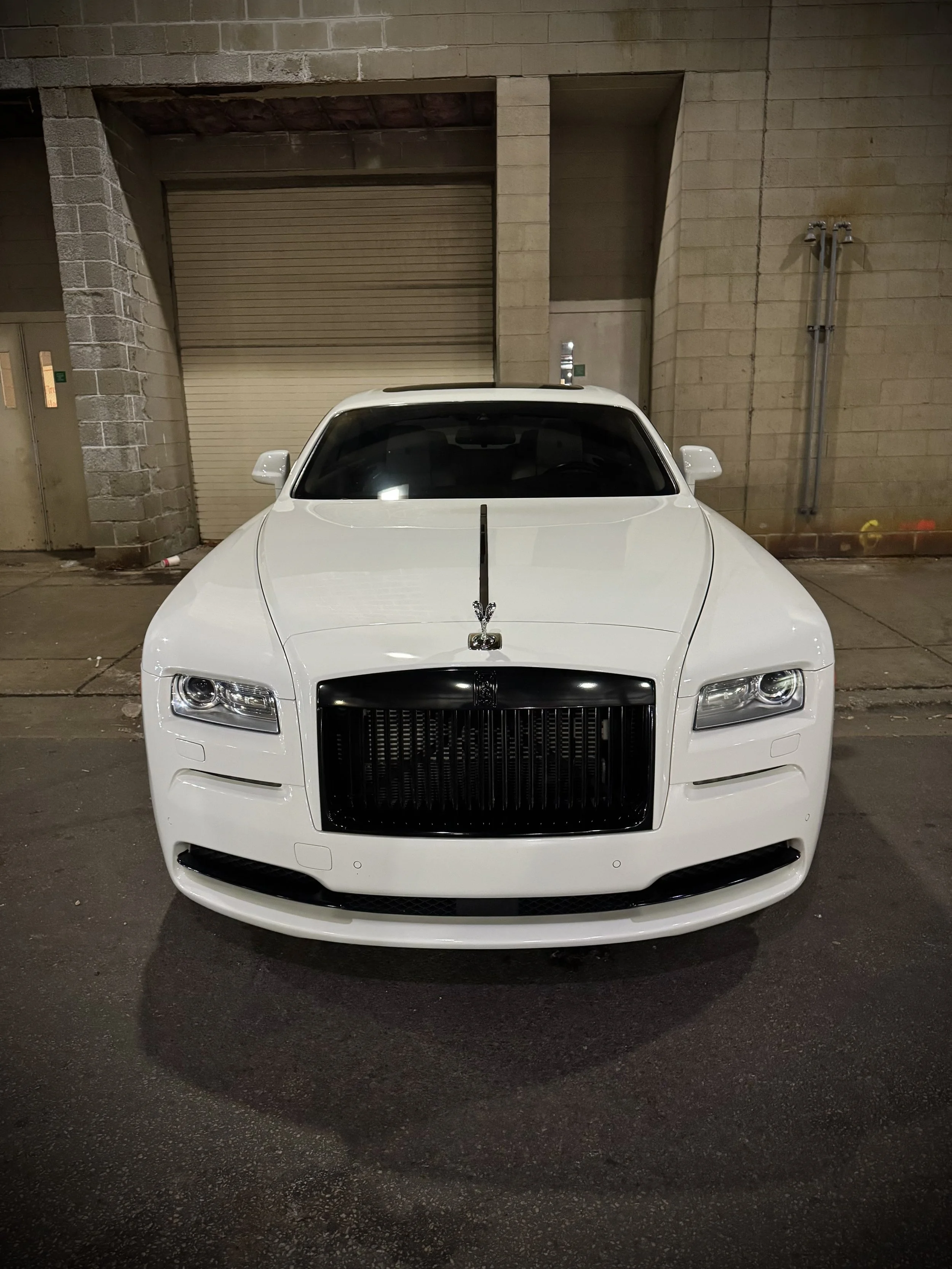 White Rolls-Royce Wraith rental from Axel Luxury parked in downtown Chicago with luxury white-on-white styling.