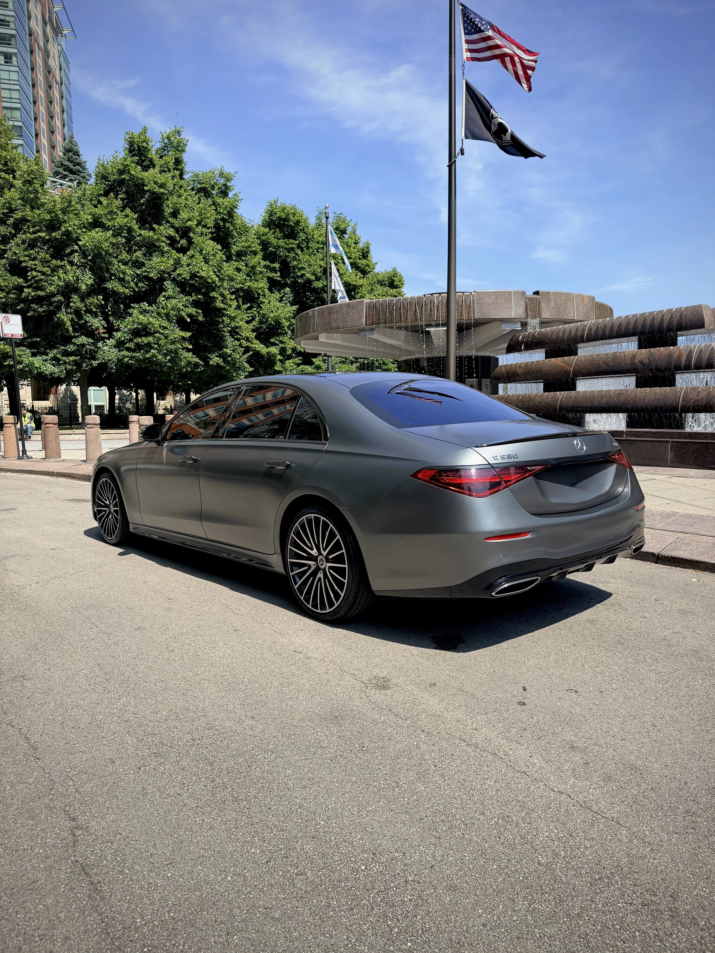 Matte Graphite Gray Mercedes-Benz S580 luxury sedan parked in downtown Chicago available for rental.