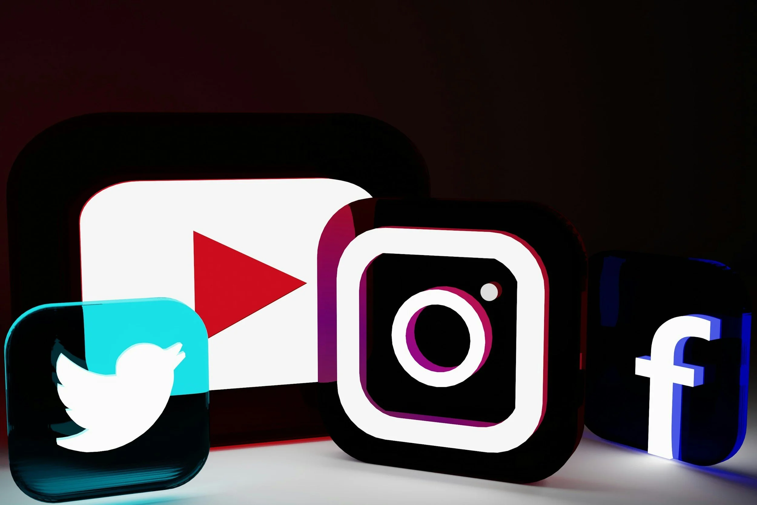 illuminated icons of popular social media platforms YouTube, Twitter, Instagram, Facebook, and TikTok, arranged side by side against a dark background.