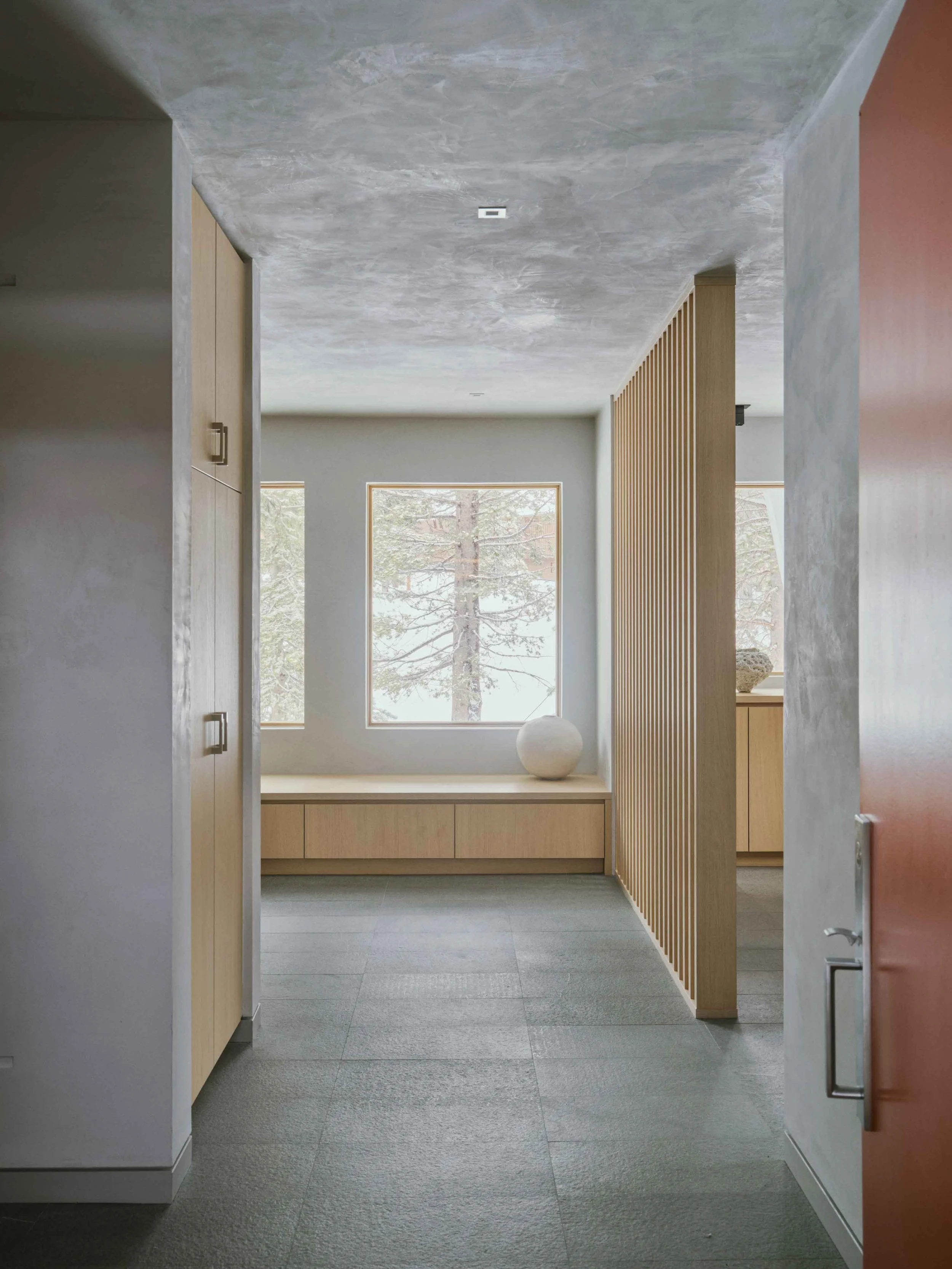 Welcoming mountain home foyer with natural materials, clean lines, and warm minimalist design influenced by European alpine style
