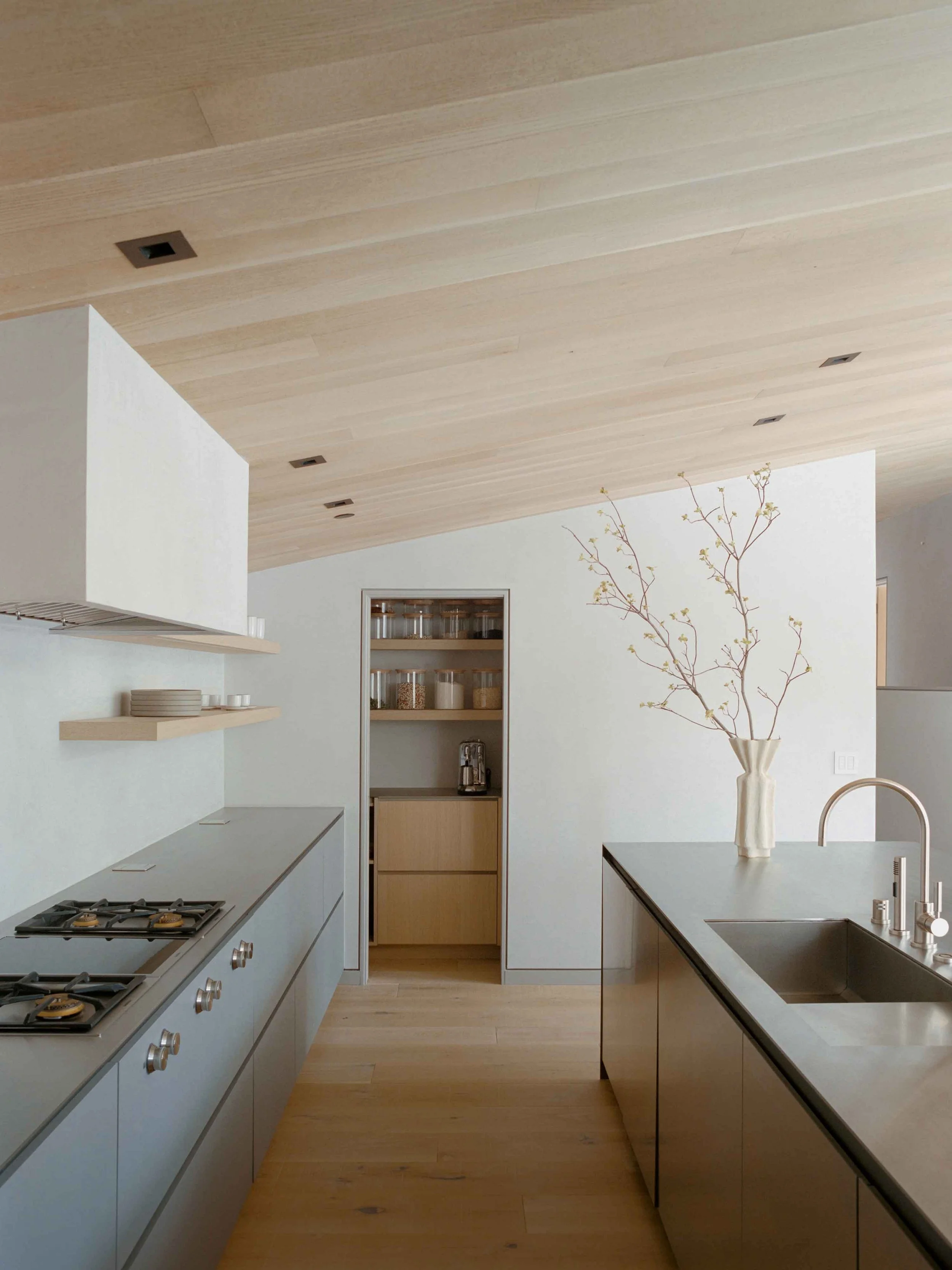 Luxury mountain kitchen with neutral cabinetry, natural stone countertops, and warm wood accents in a modern alpine style