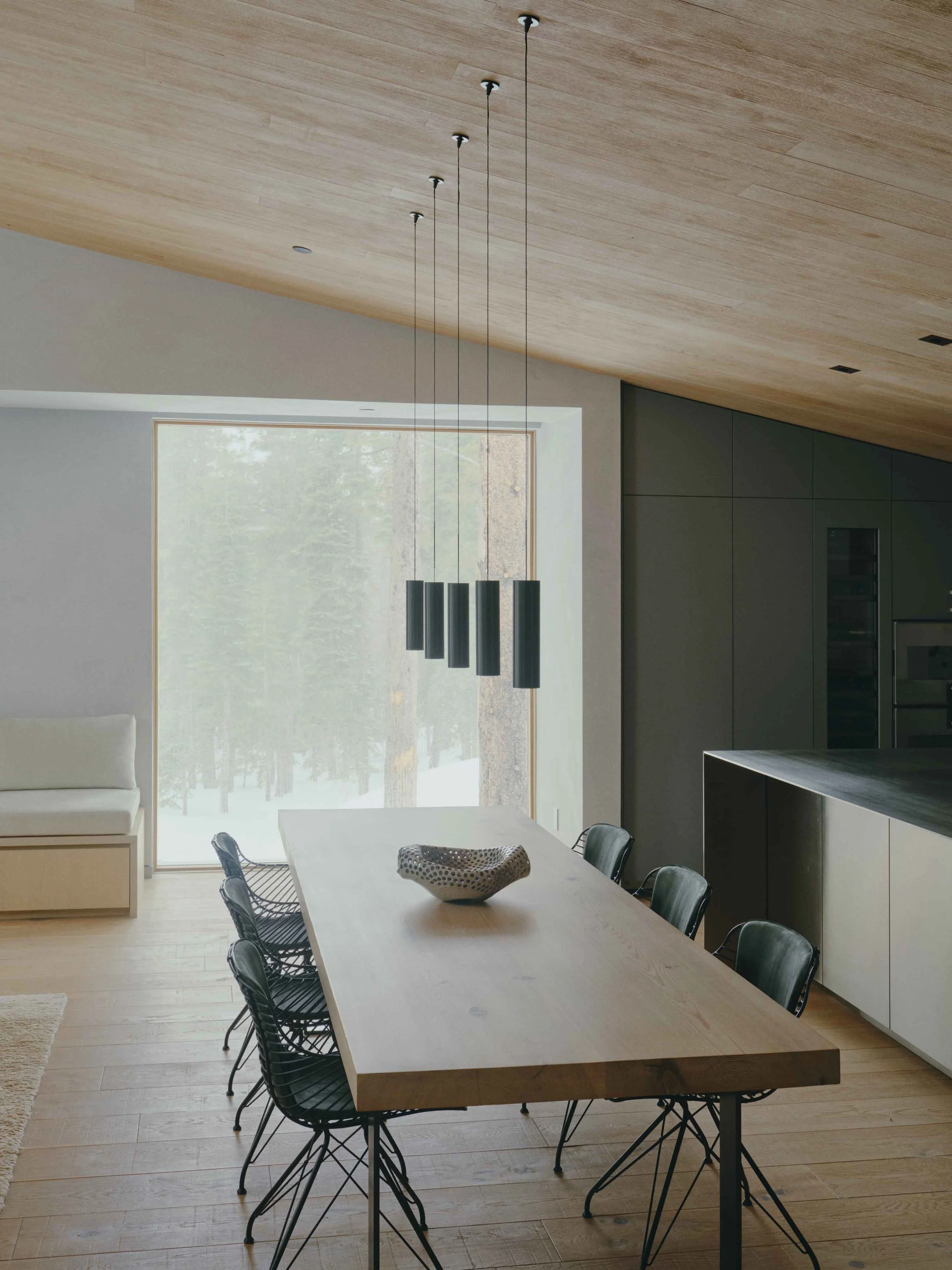Elegant dining room with sculptural lighting, neutral tones, and layered textures in a refined alpine-inspired interior