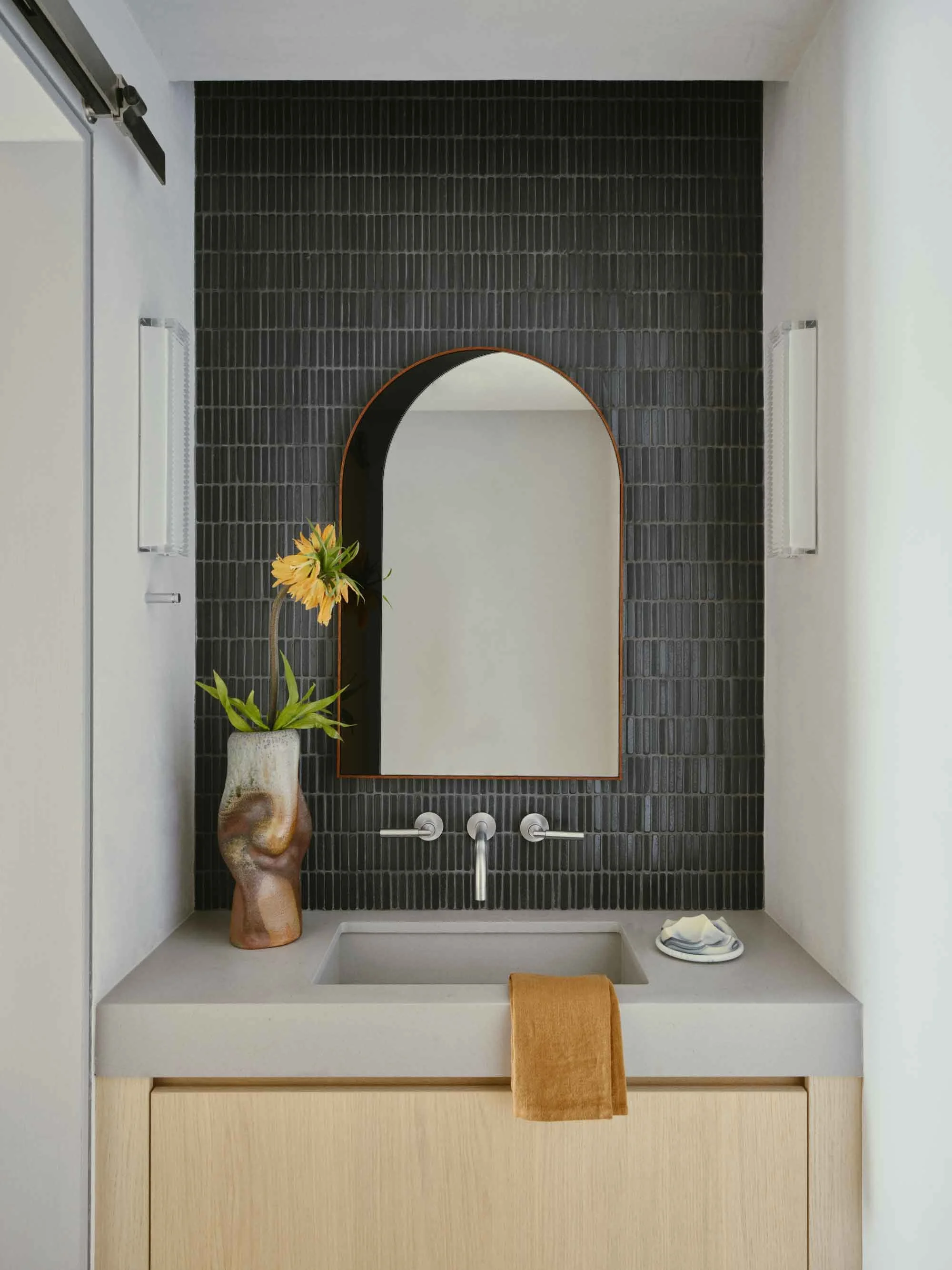 Modern powder room with natural stone, warm wood finishes, and refined alpine-inspired details