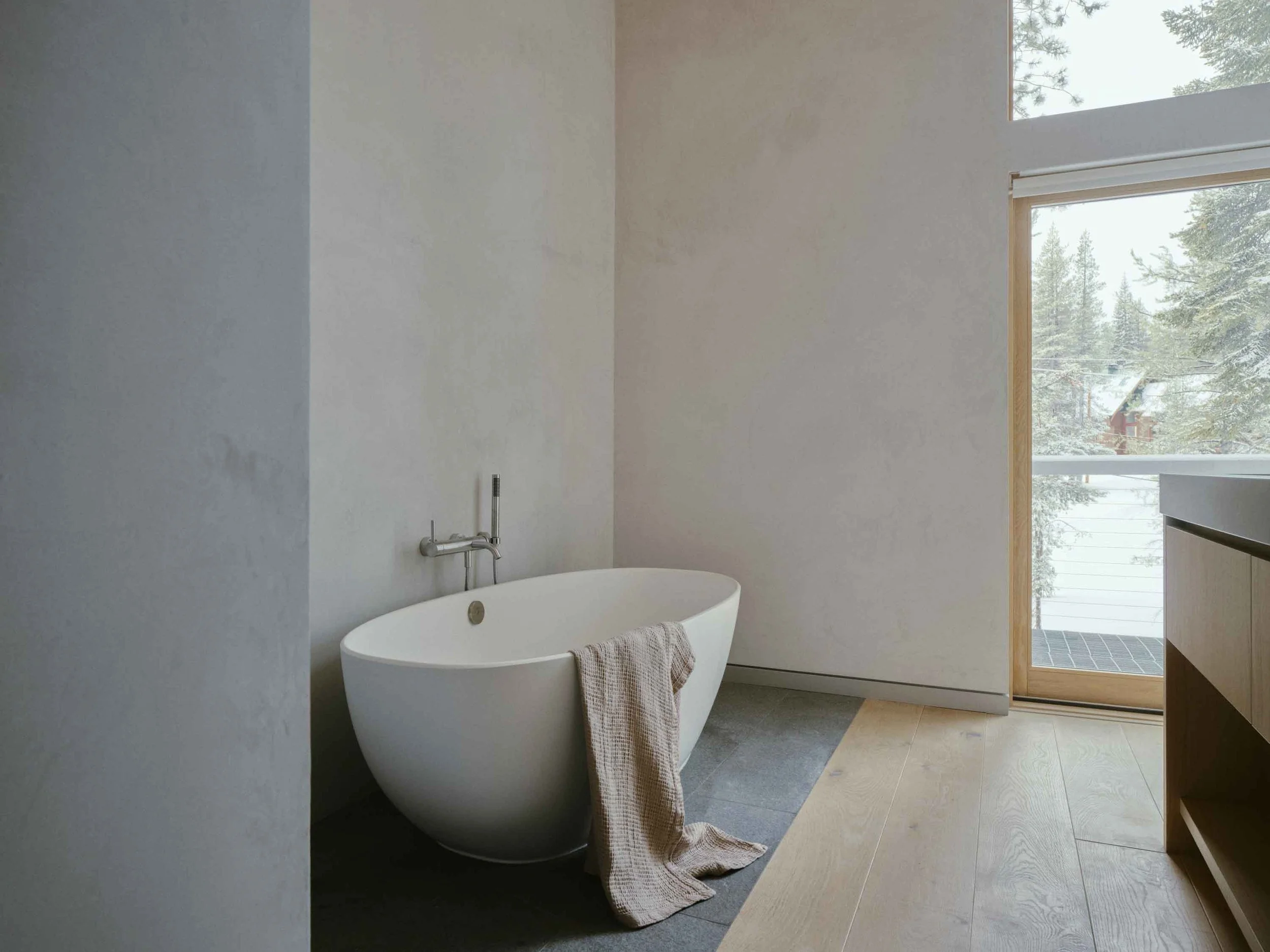 Spa-like primary bathroom with natural stone, soft lighting, and warm textures inspired by a luxury alpine retreat