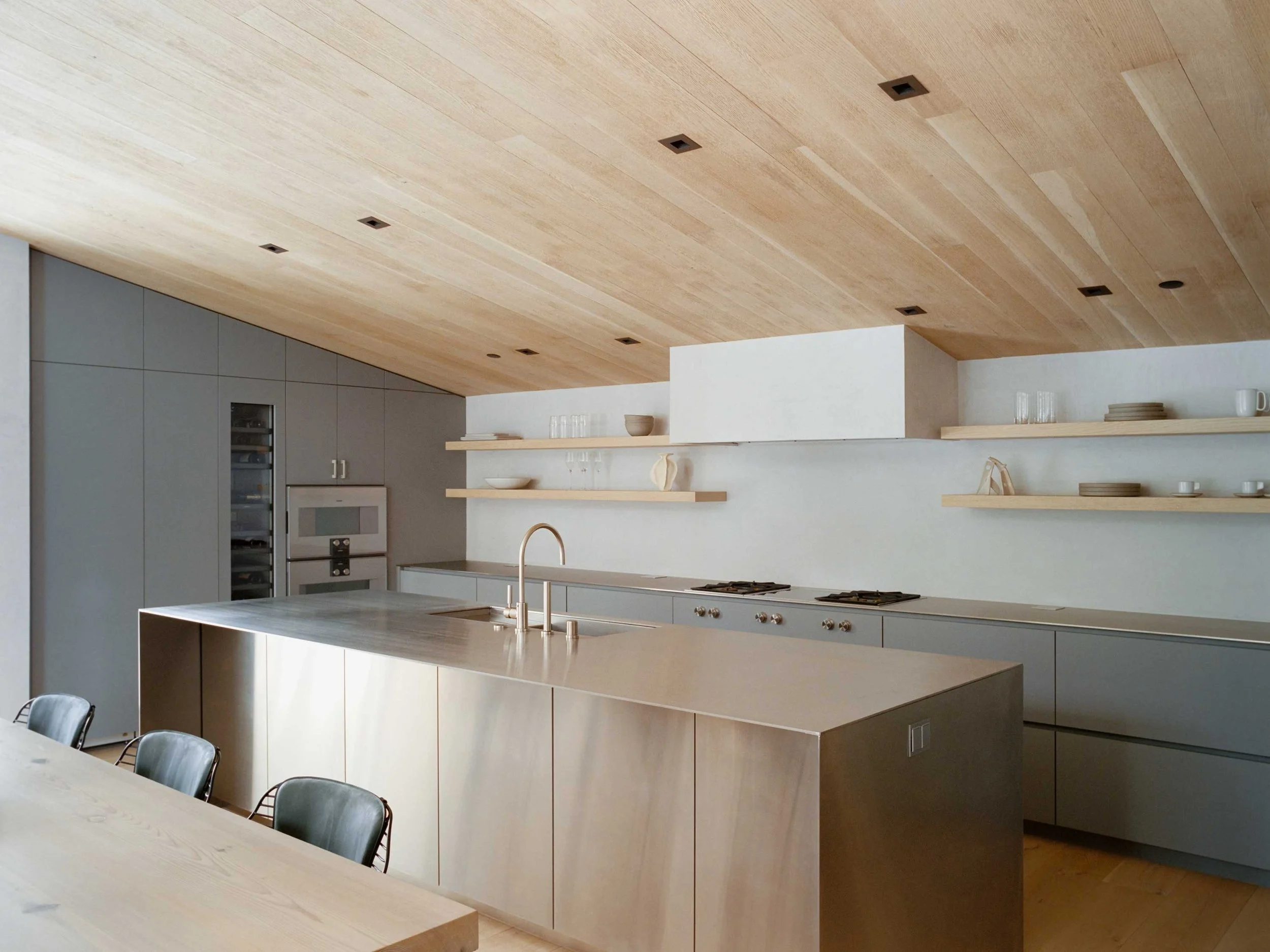 Luxury mountain kitchen with neutral cabinetry, natural stone countertops, and warm wood accents in a modern alpine style