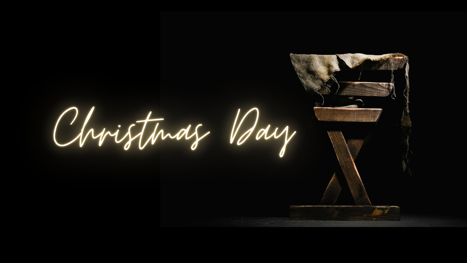 A neon sign reading 'Christmas Day' next to a rustic wooden manger with a cloth cover, set against a black background.