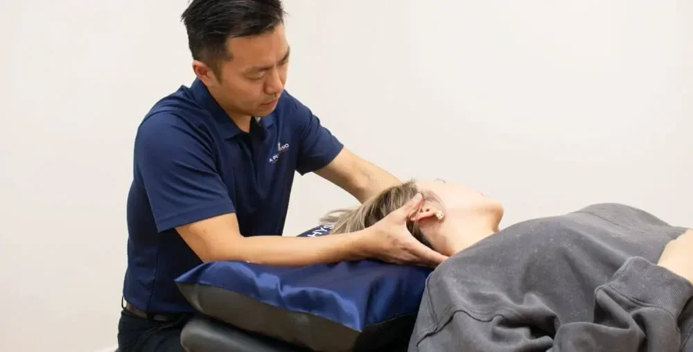 A man providing chiropractic care to a woman lying on her side on a treatment table.