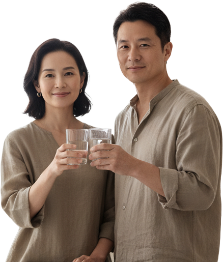 A man and woman holding glasses of water, smiling at the camera.