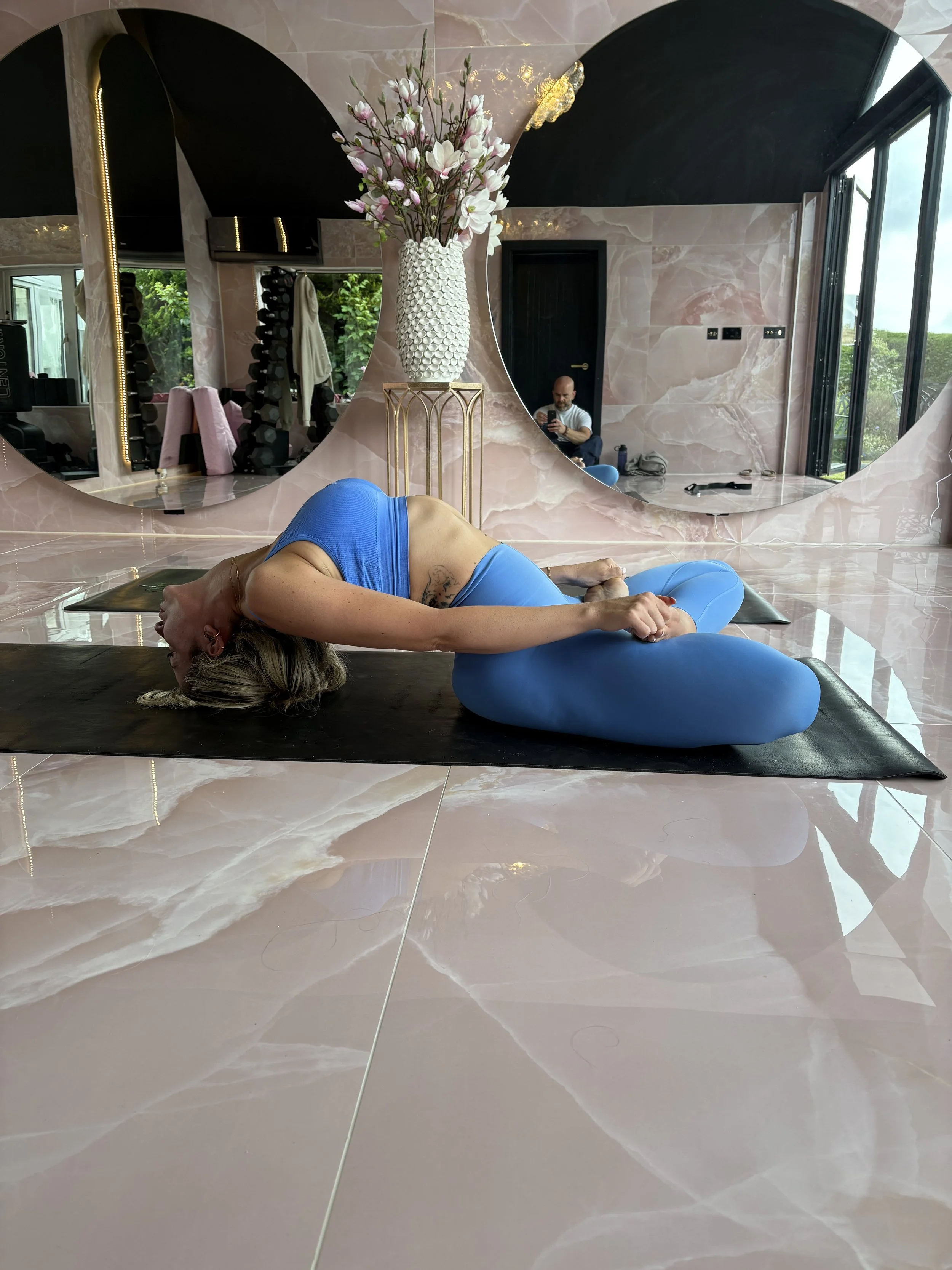 A woman practicing yoga in a room, bending backward over a chair in a bridge pose on a yoga mat.