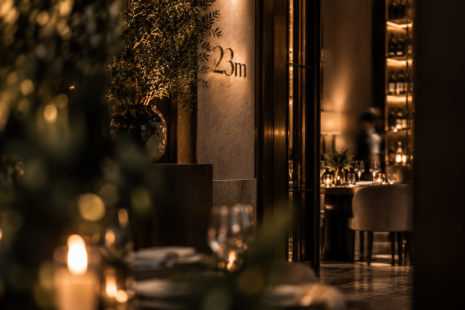 Intimate hospitality entrance illuminated by warm architectural lighting, refined natural materials and curated greenery, representing exceptional experiences, gracious service and enduring hospitality through T&M Lifestyle.