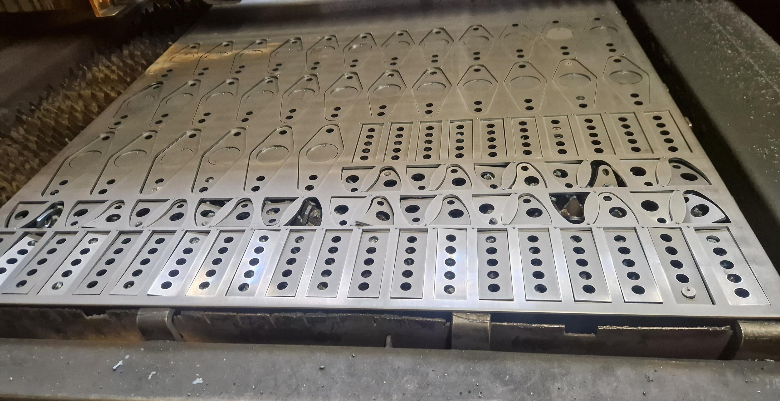 A metal dominoe rack with multiple dominoes laid out, some slightly tilted or misaligned.