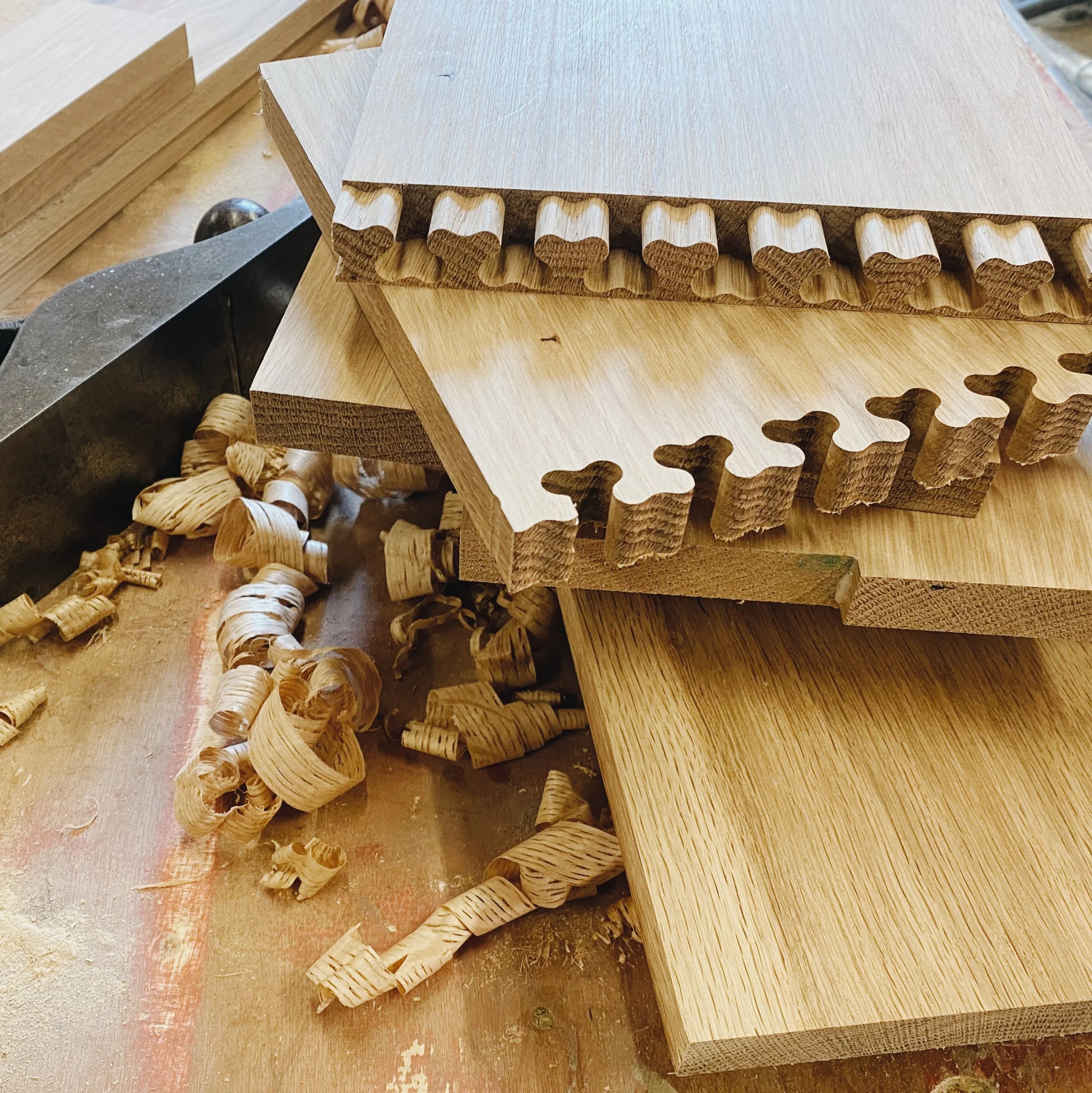 Close-up of wooden woodworking pieces, some with heart-shaped carvings, on a workbench in a woodworking shop.