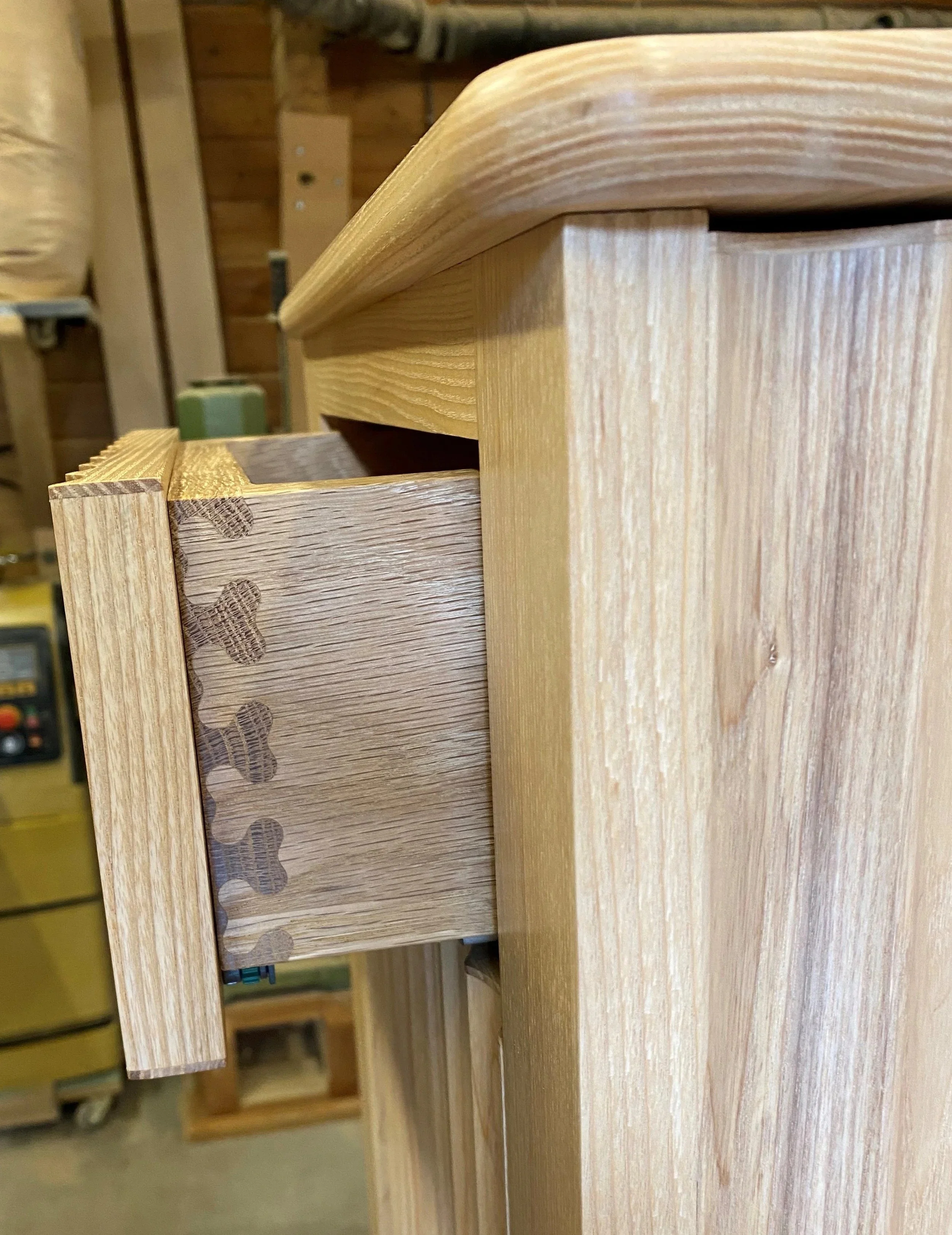 Close-up of a wooden cabinet drawer with dovetail joints in the corner, showing the natural wood grain and craftsmanship.