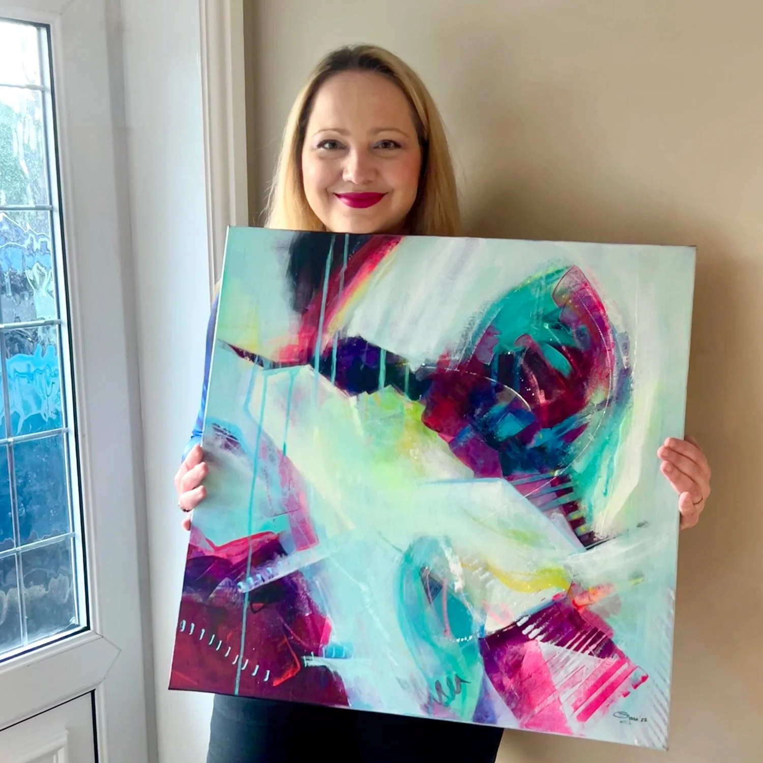 Artist Gorana Law holding her vibrant abstract painting called Wild Whirl.