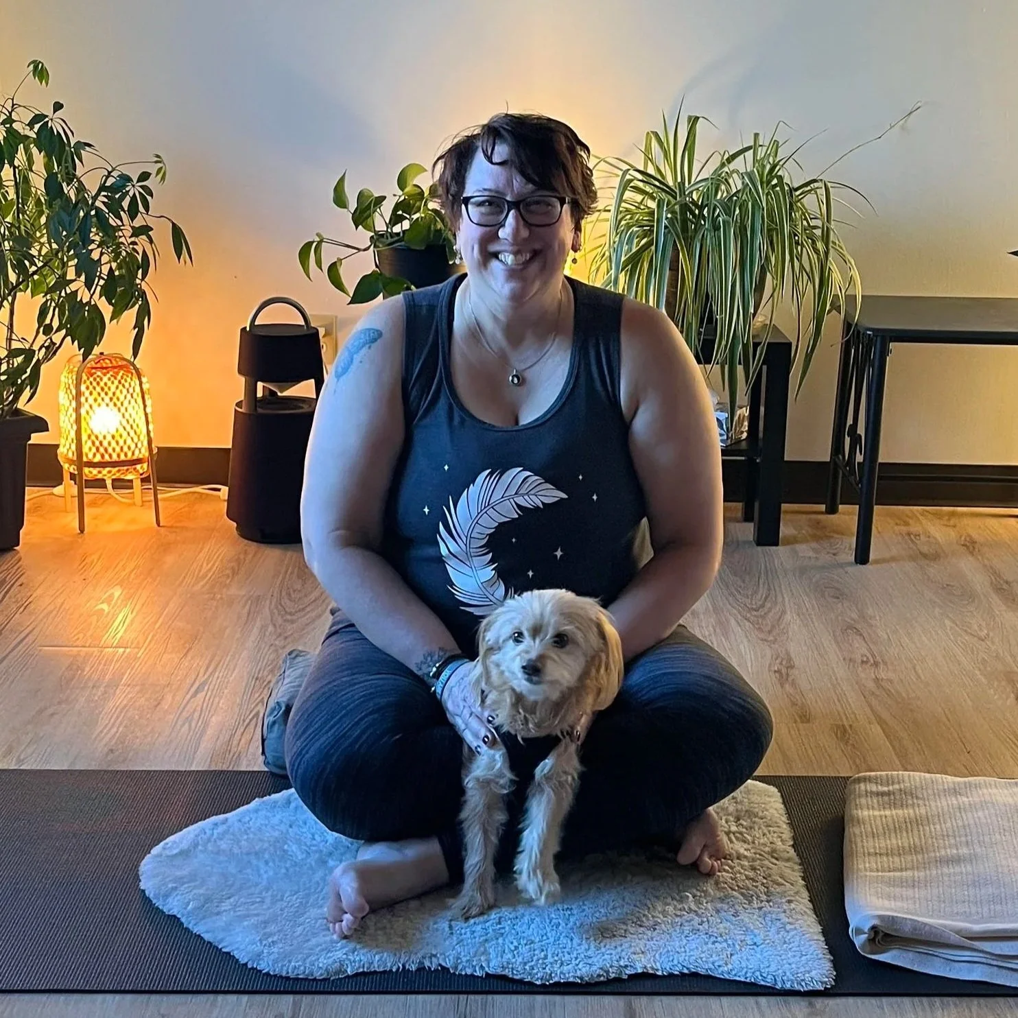 picture of yoga instructor michelle and yogi dog. sitting on a yoga mat in the yoga studio