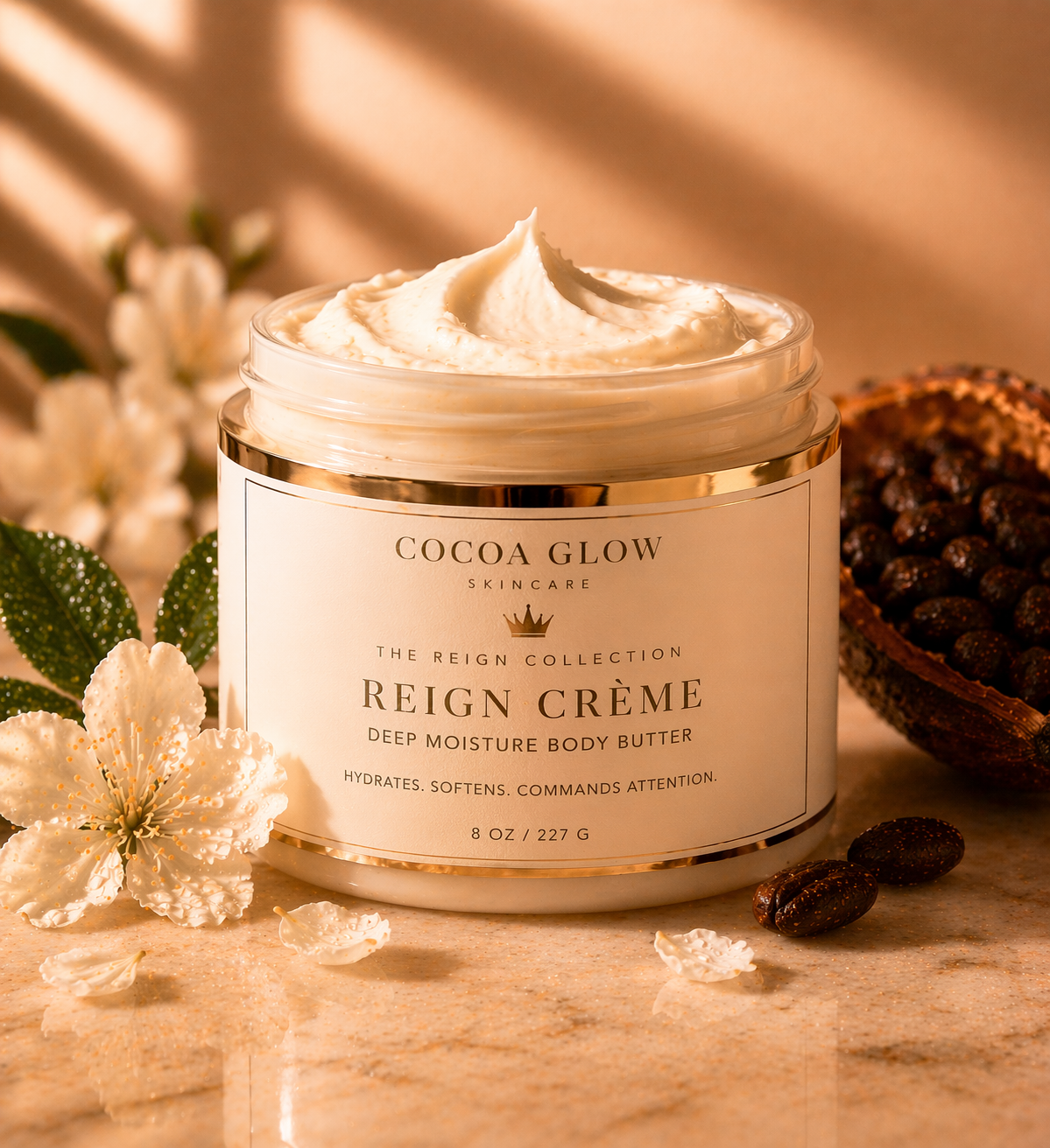 A jar of Cocoa Glow Reign Crème deep moisture body butter with a creamy texture, surrounded by flowers, a cacao pod, and cacao beans on a marble surface.