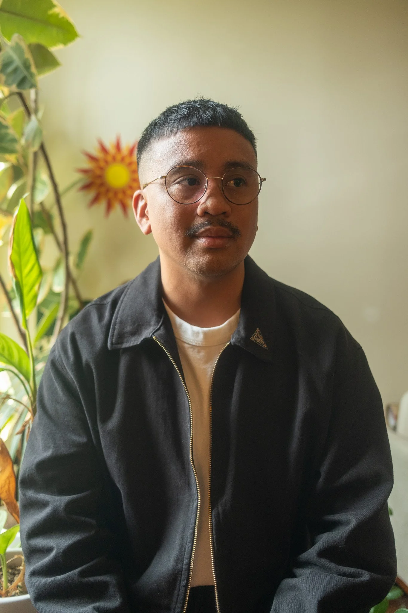 Portrait of Chris Datiles, Los Angeles IFS Therapist, in front of a ficus tree and plant decal.