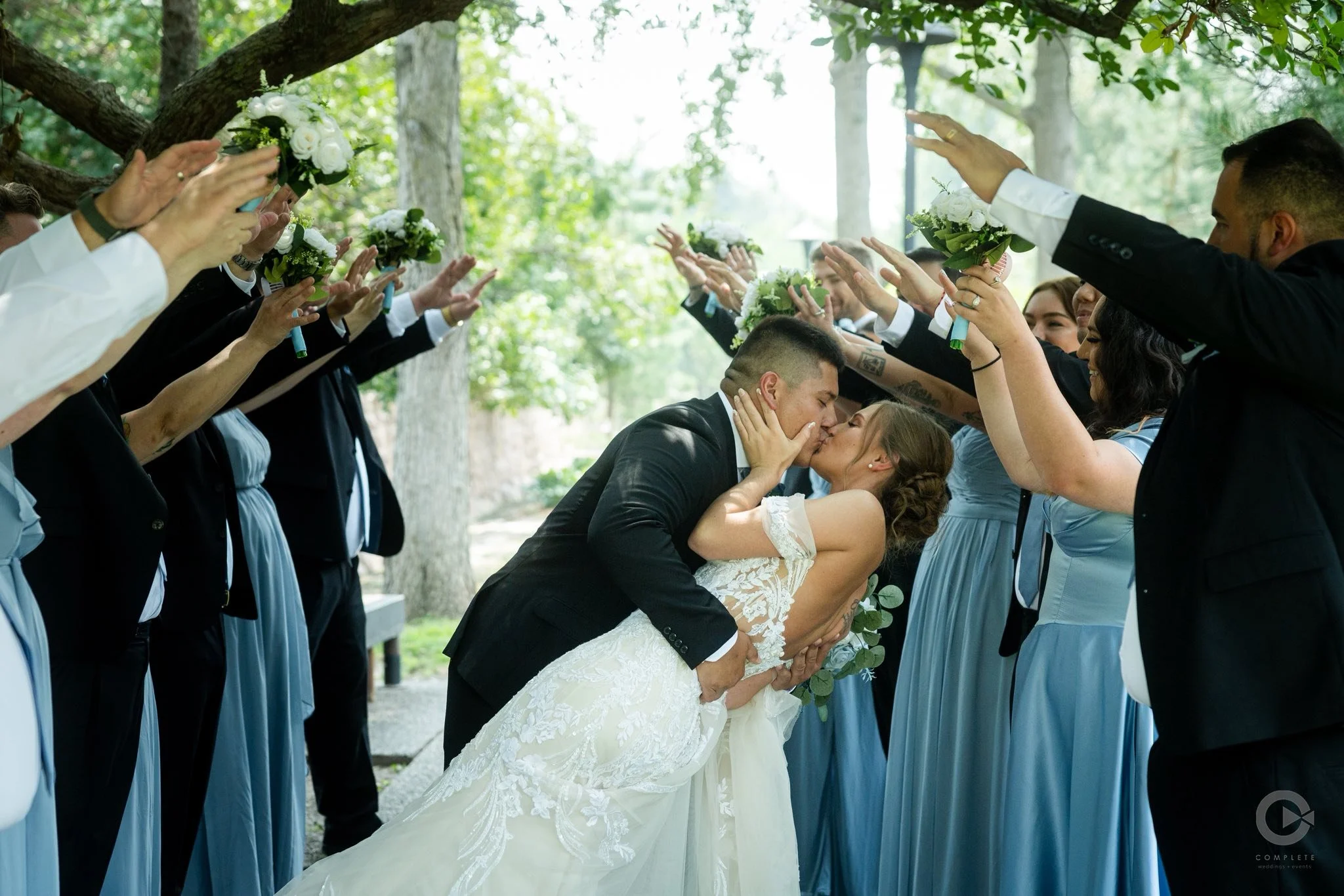 Bride and groom celebrating their wedding at LuxeFalls Venue in Sioux Falls, surrounded by bridesmaids in blue dresses.