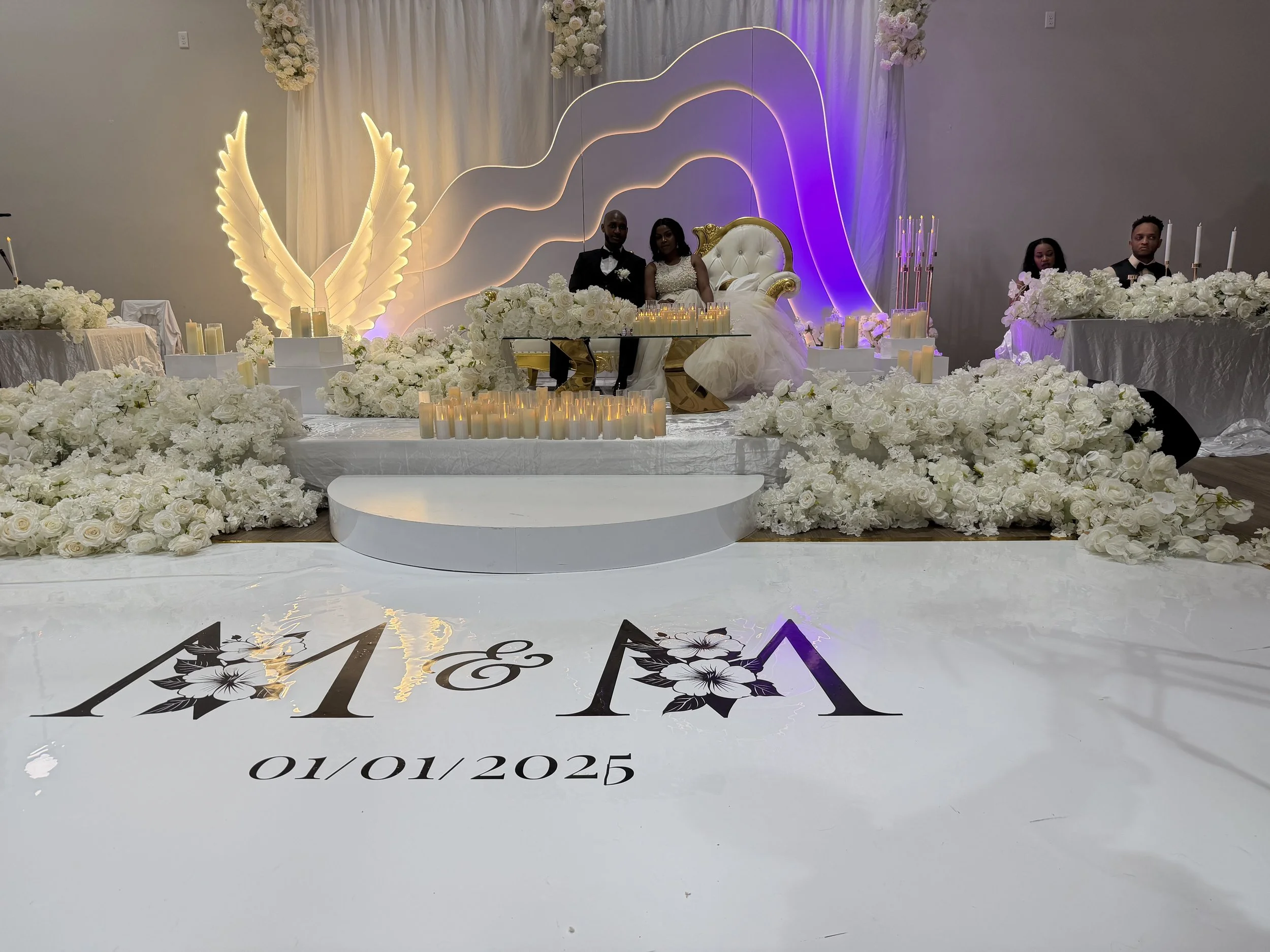 Elegant wedding reception design at LuxeFalls Venue in Sioux Falls, showcasing a white floral stage, candlelit head table, and modern luxury décor for a timeless and romantic celebration.