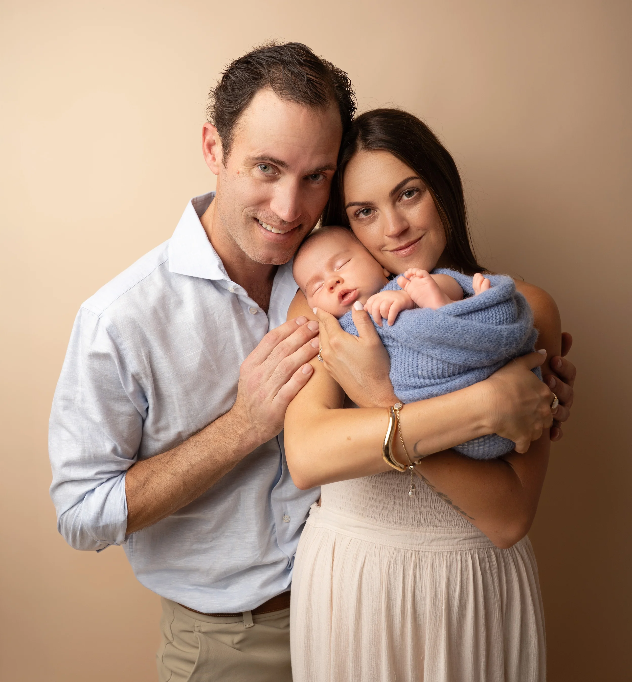 mom, dad, and baby posed in embrace during studio session with raleigh newborn photographer