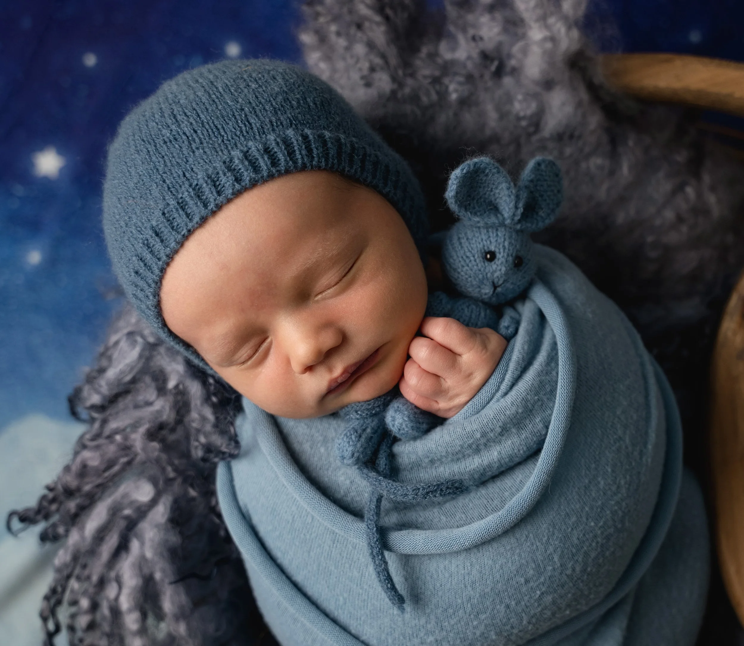 newborn baby in blue holding bunny stuffy during session with Wake Forest Newborn Photographer