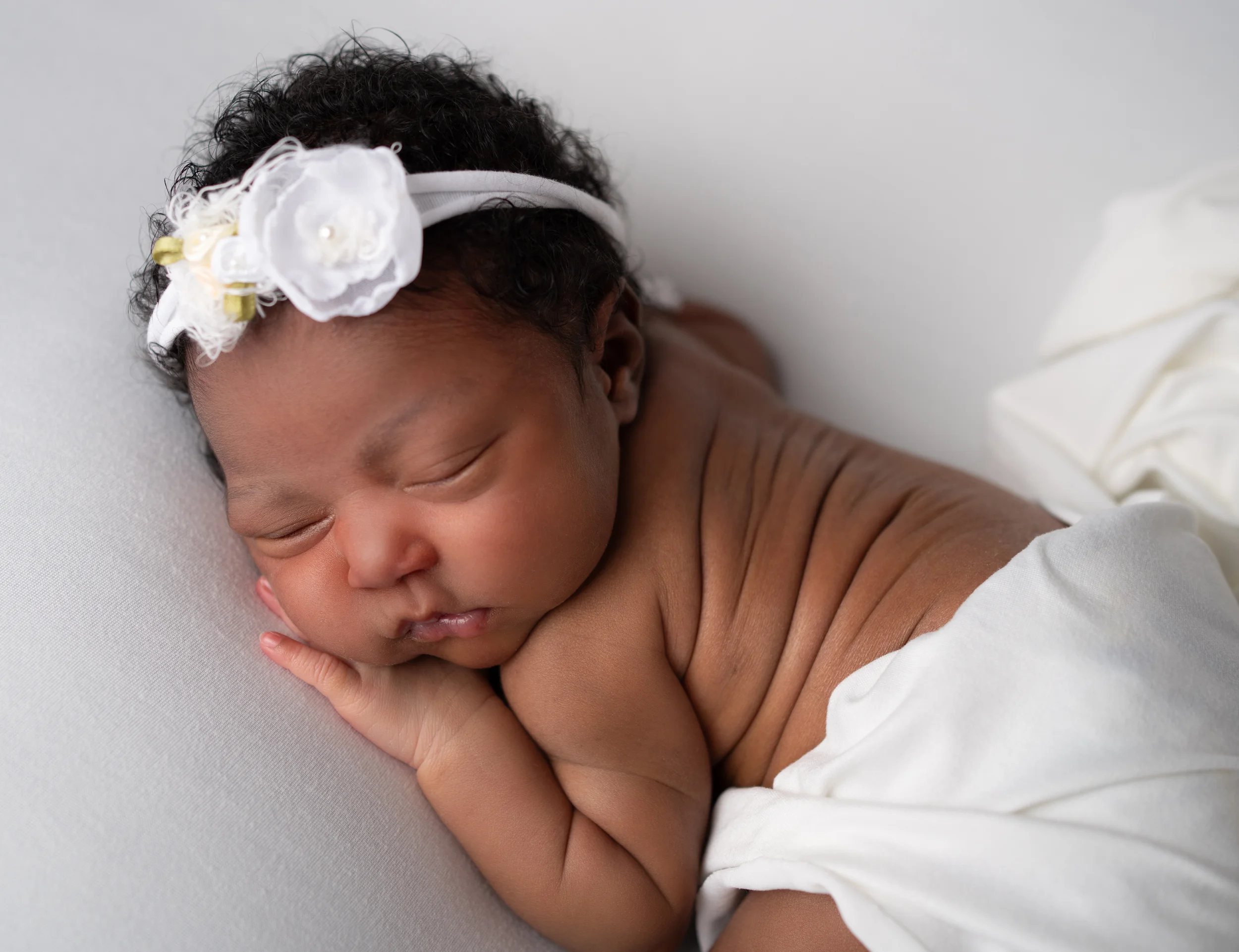 baby girl posed in white with floral headband during session with raleigh newborn photographer