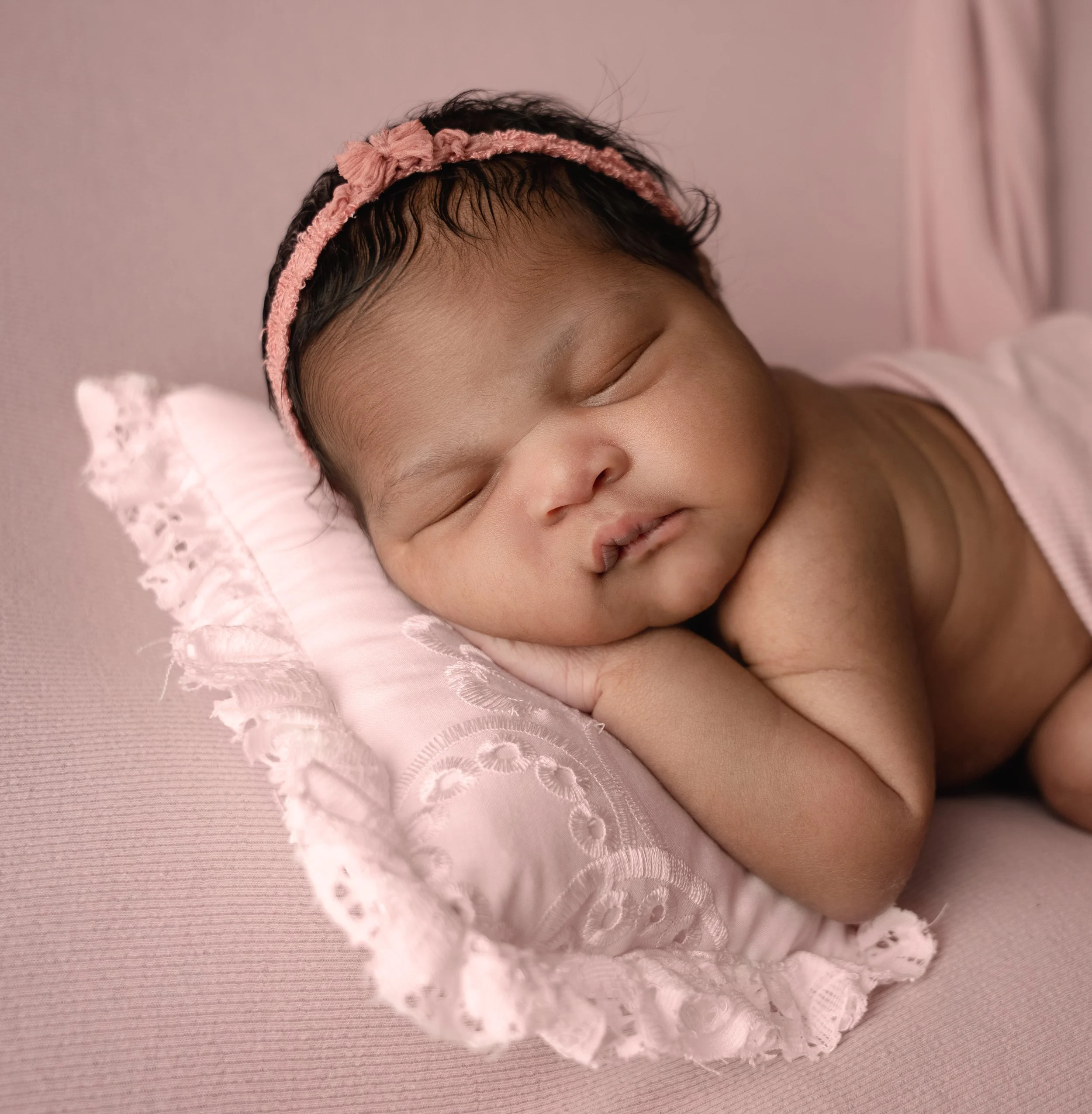 baby girl in pink posed on a pillow during session with raleigh newborn photographer