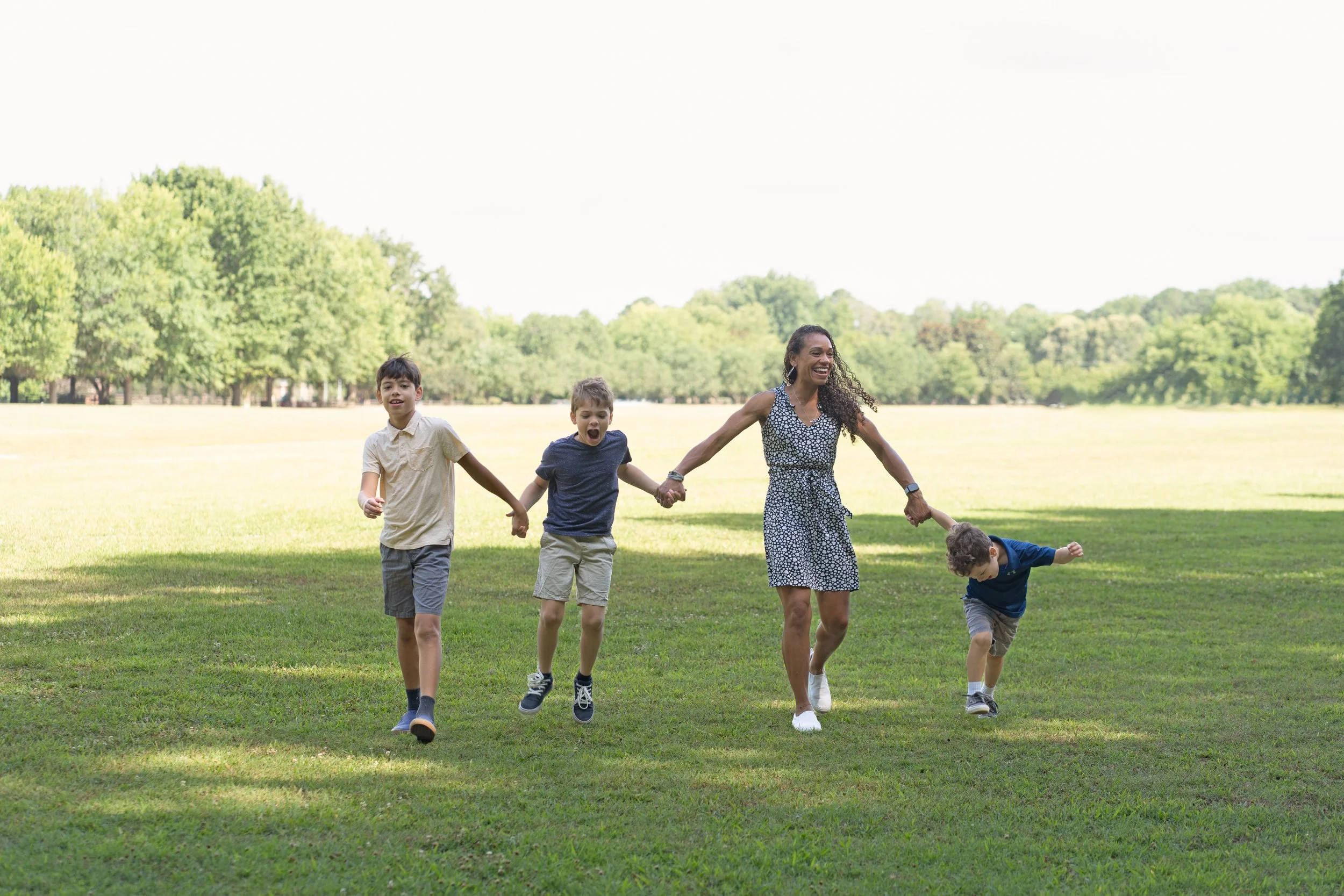 mom and three boys walking in the park during session with raleigh newborn photographer