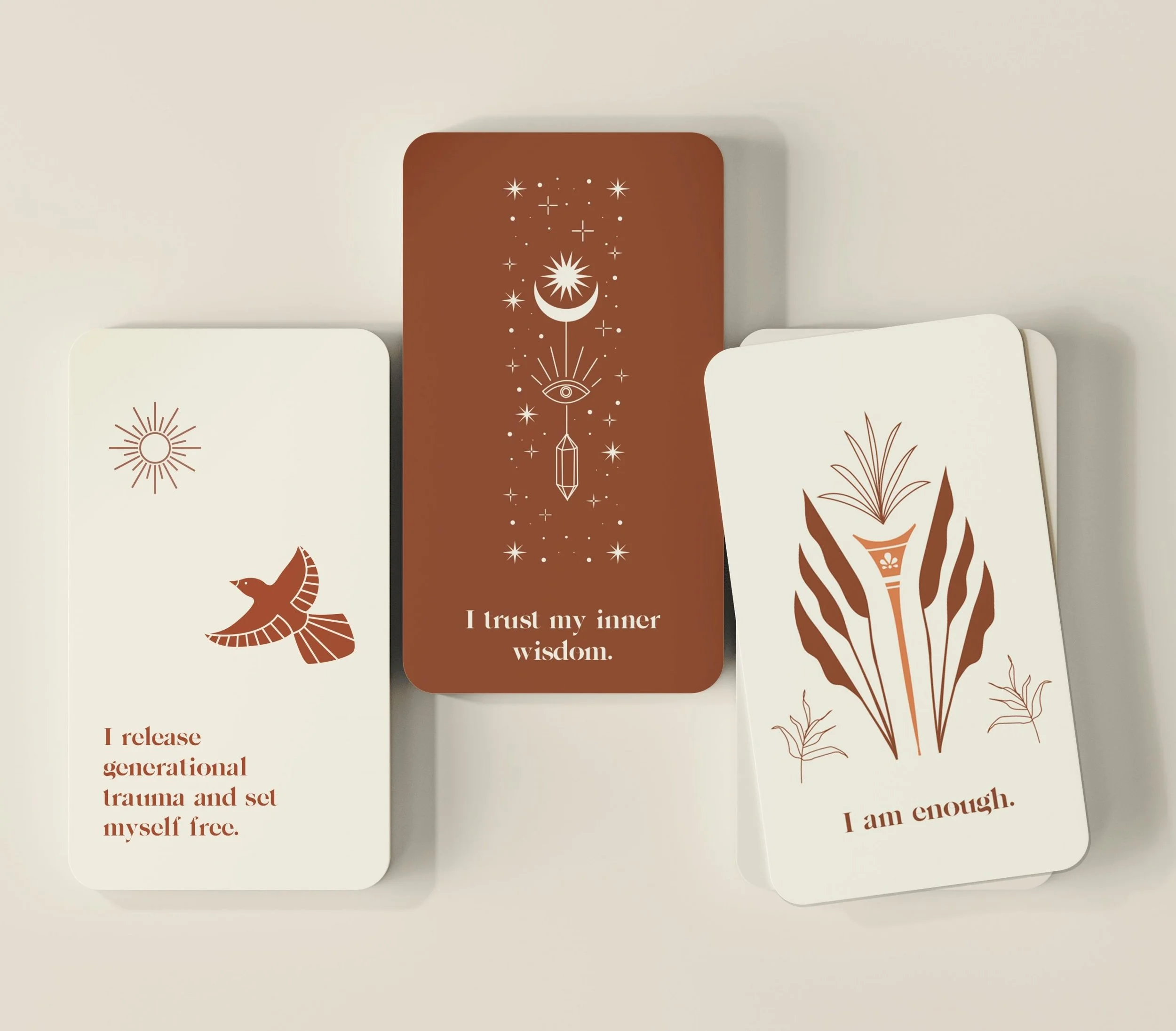 Three affirmation cards with brown and white backgrounds featuring spiritual and healing messages and minimalistic illustrations, placed on a white surface.