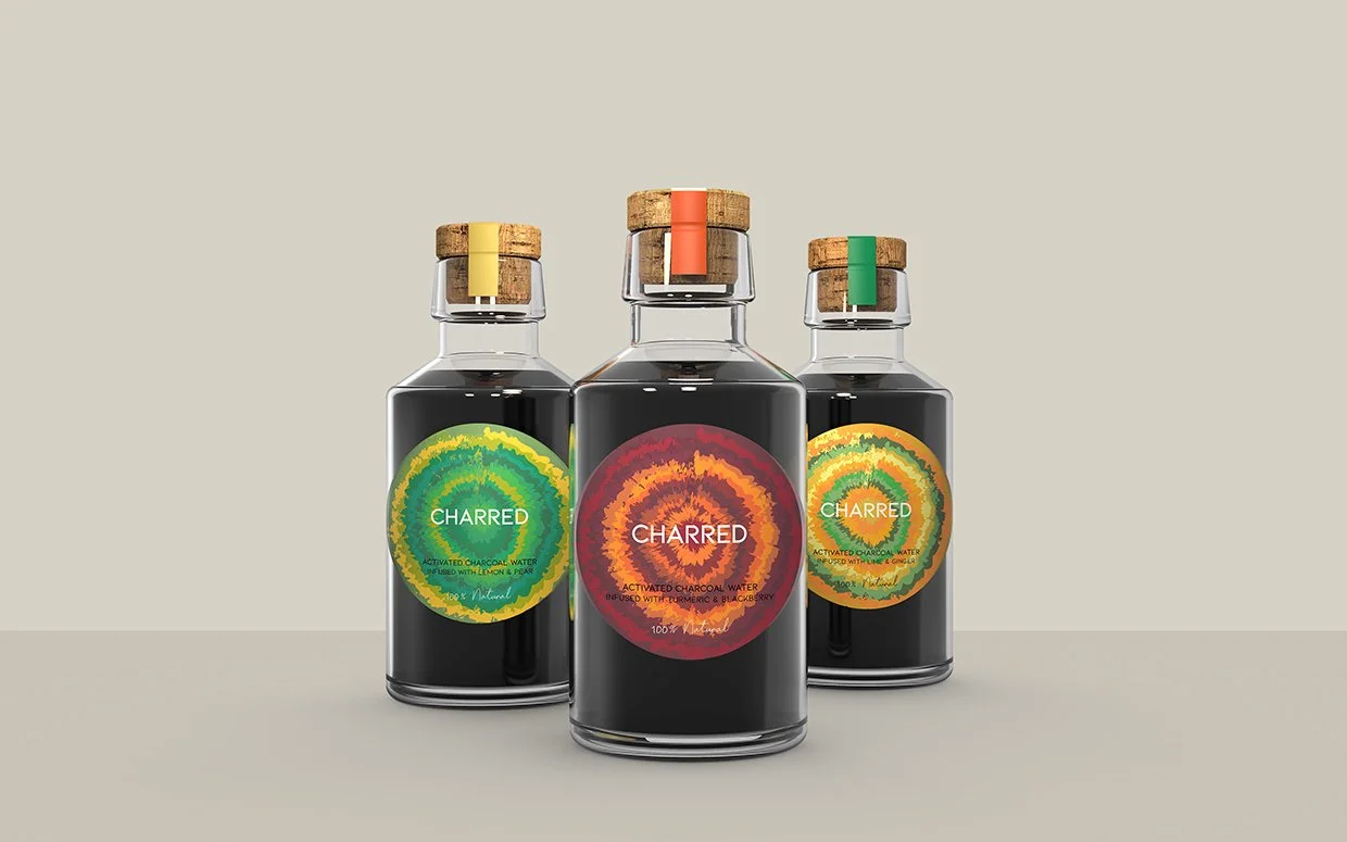 Three bottles of Charred activated charcoal water with colorful labels and cork stoppers against a neutral background.