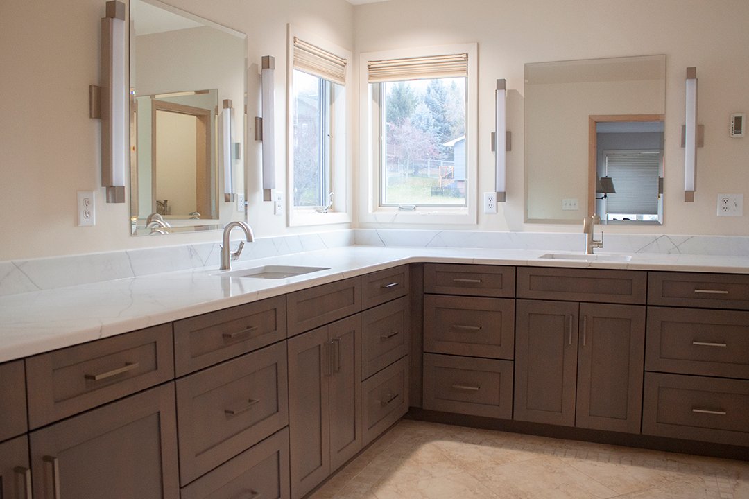 The master bathroom gained a full facelift with dark wood cabinets and white granite countertops, new sink fixtures and sleek lighting around the mirrors.