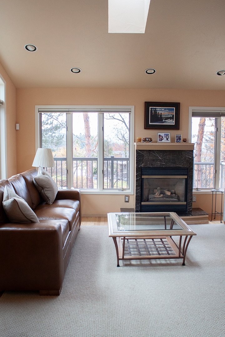 The living room features high ceilings, large windows and a cozy fireplace.