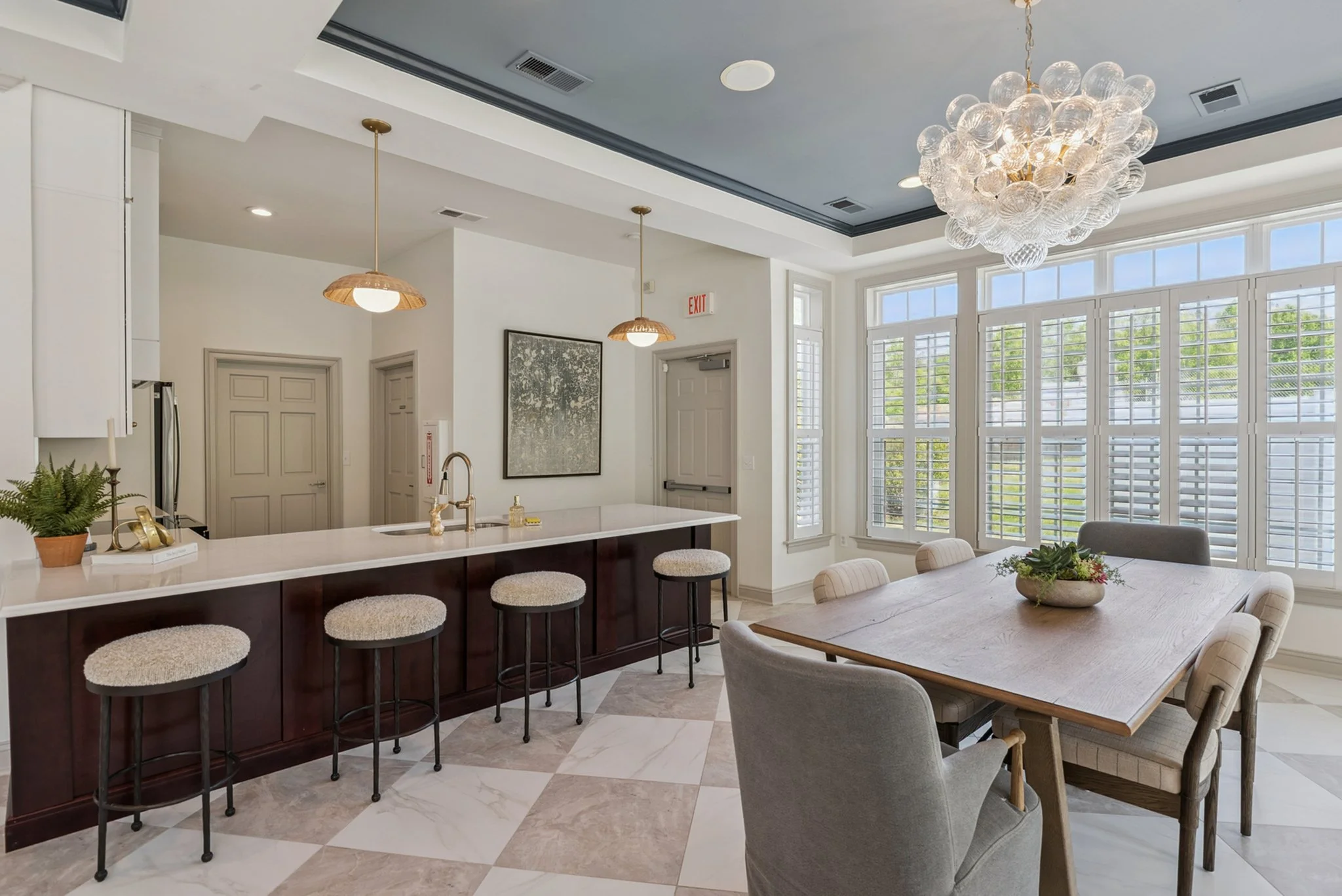 Open-concept kitchen and dining area with large windows, chic chandelier, and modern decor.
