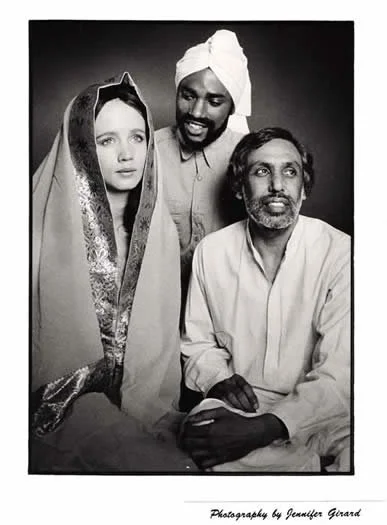 Black and white photograph of a woman in traditional attire with head covering, and two men, one wearing a turban, in a studio portrait setting.