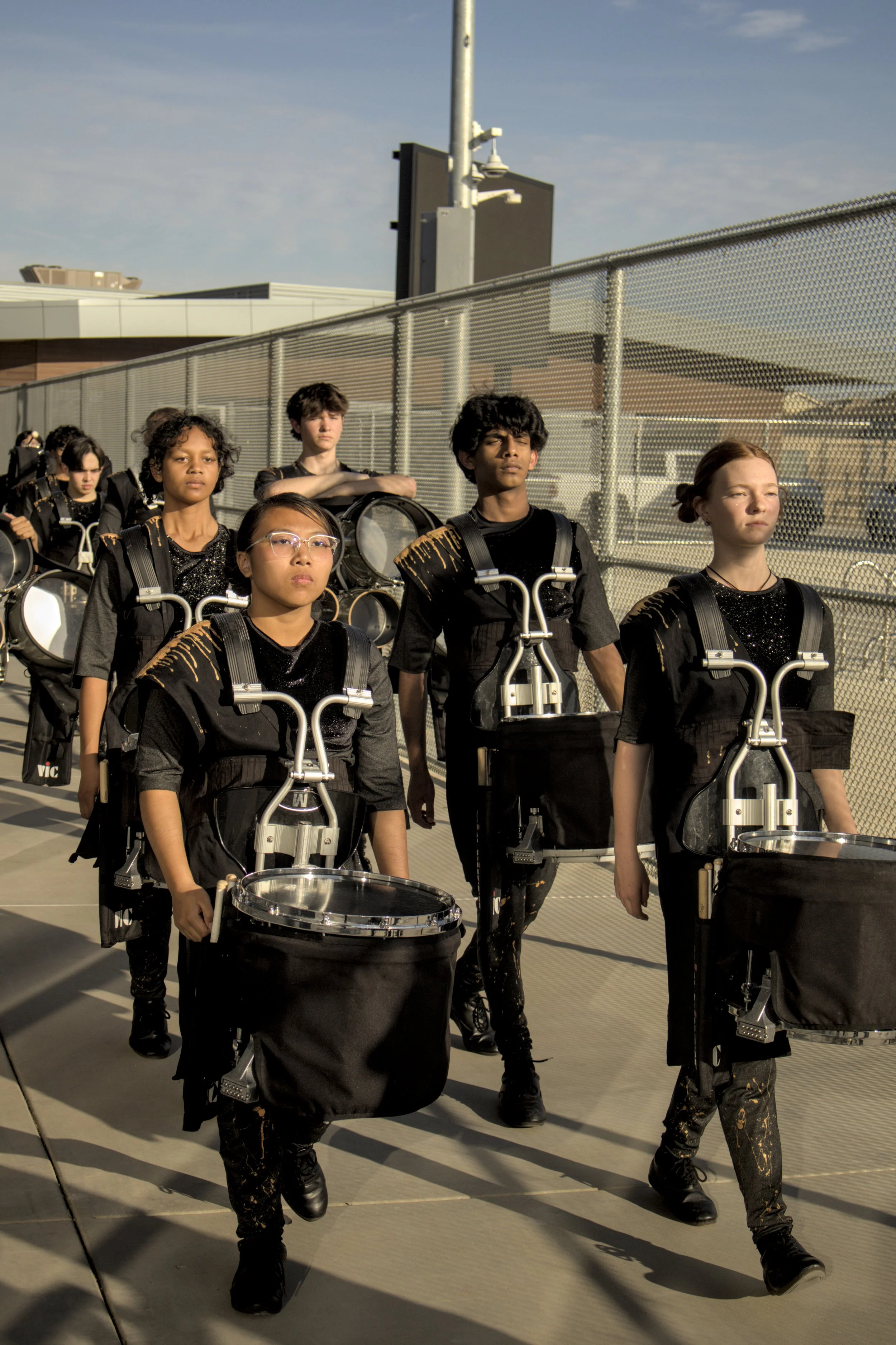 Group of young marching band drummers in uniform walking outdoors.