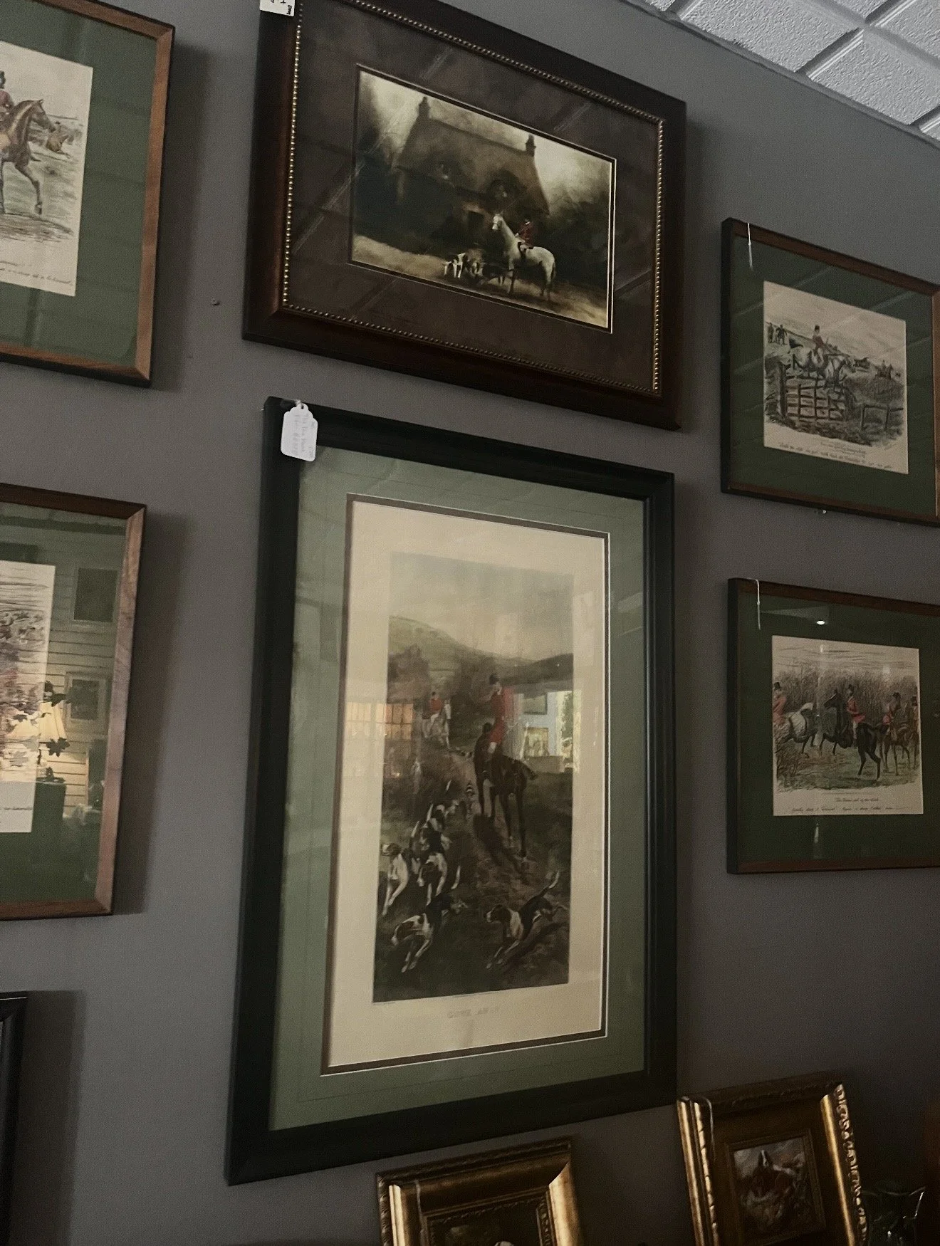 Gallery wall with framed vintage-style artwork depicting outdoor scenes and horse riding.