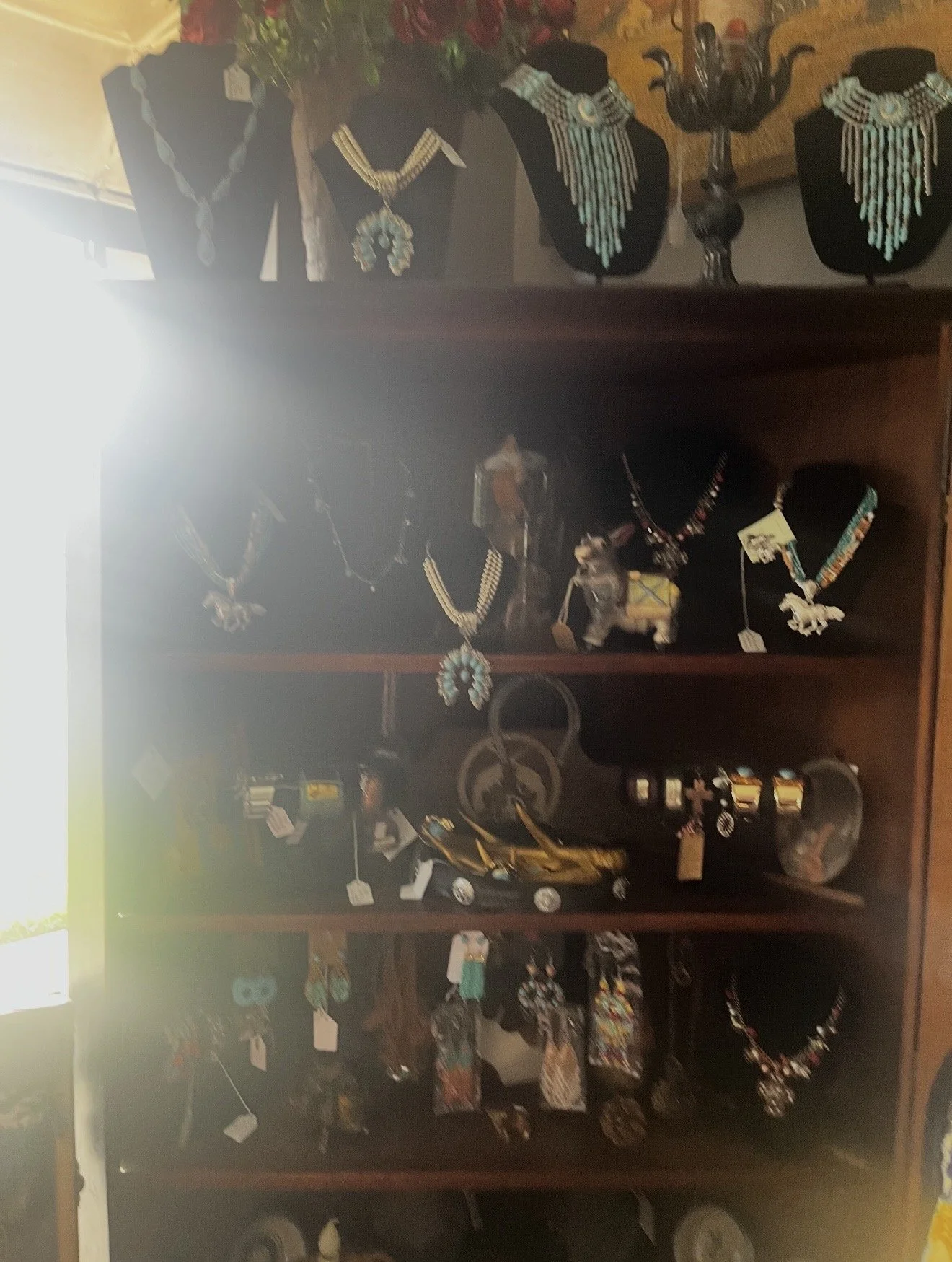 Display of jewelry including necklaces and beaded accessories on black bust stands and in display cases.