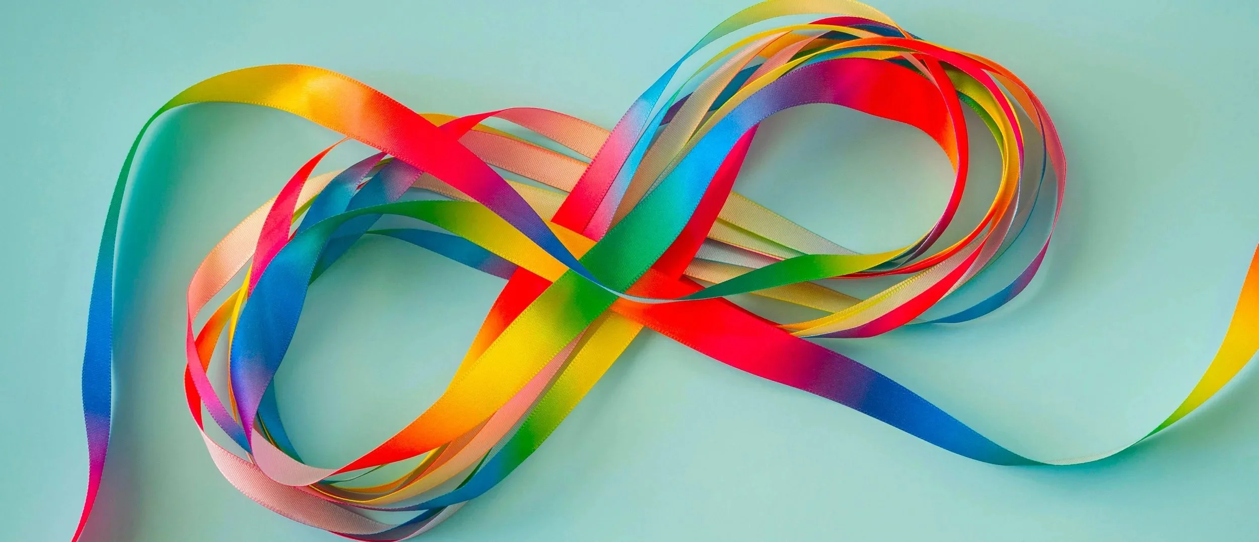 Colorful rainbow ribbons tangled on a light blue background.